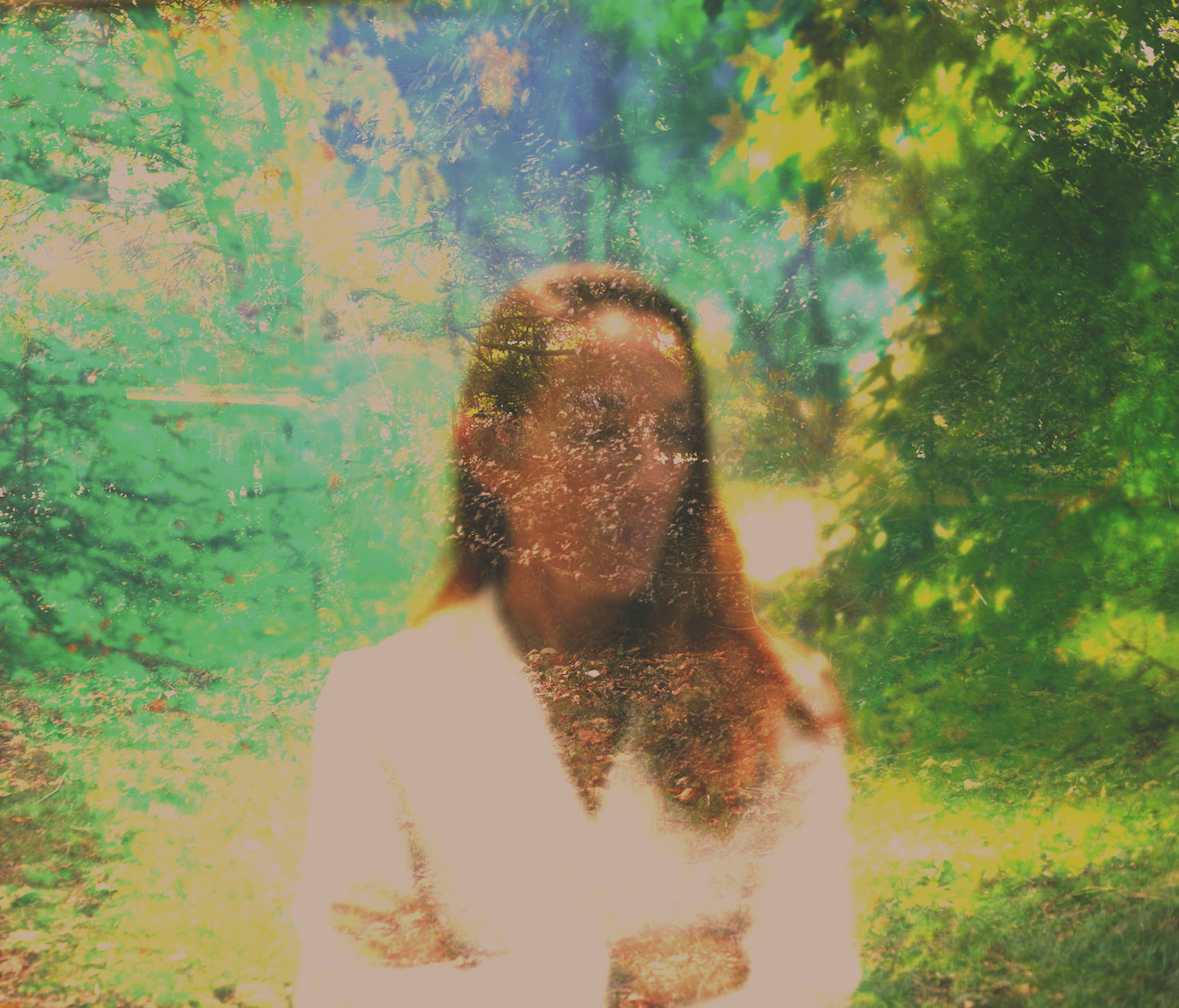 A double exposure photograph of a woman with long hair and a white shirt, superimposed over a green, leafy outdoor scene with trees and sunlight.