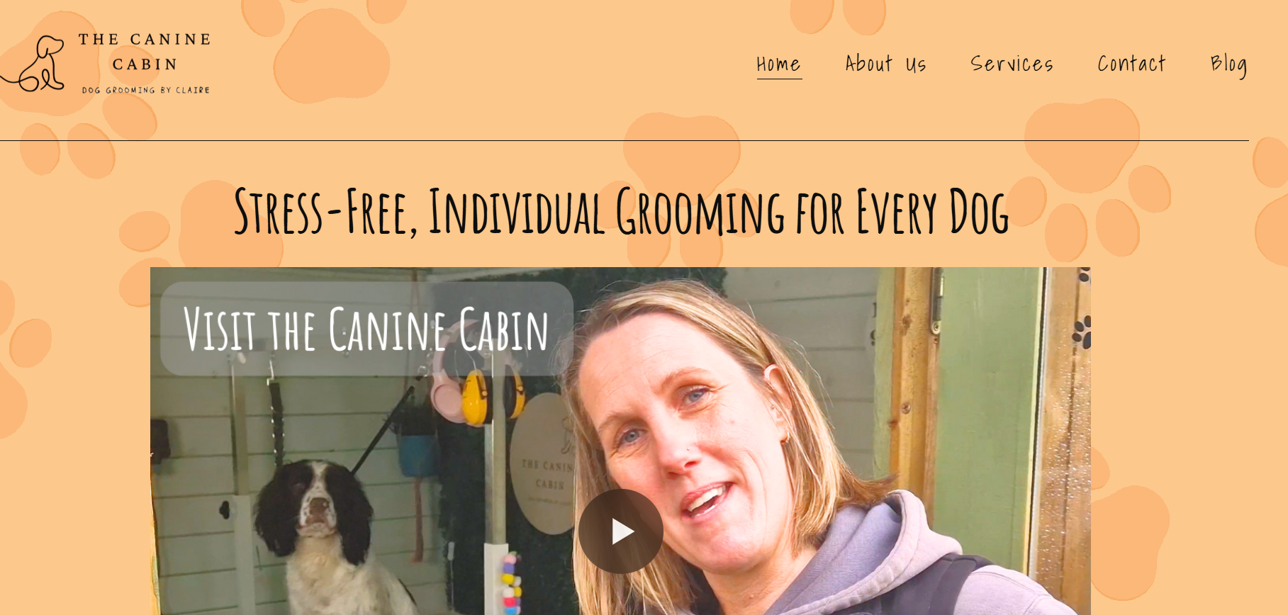 Screenshot of a website homepage for The Canine Cabin, offering stress-free, individual dog grooming. The page features a woman smiling with a dog in a grooming station, and a caption stating "Visit the Canine Cabin." The website has a peach-colored background with paw print patterns, navigation links at the top, including Home, About Us, Services, Contact, and Blog.
