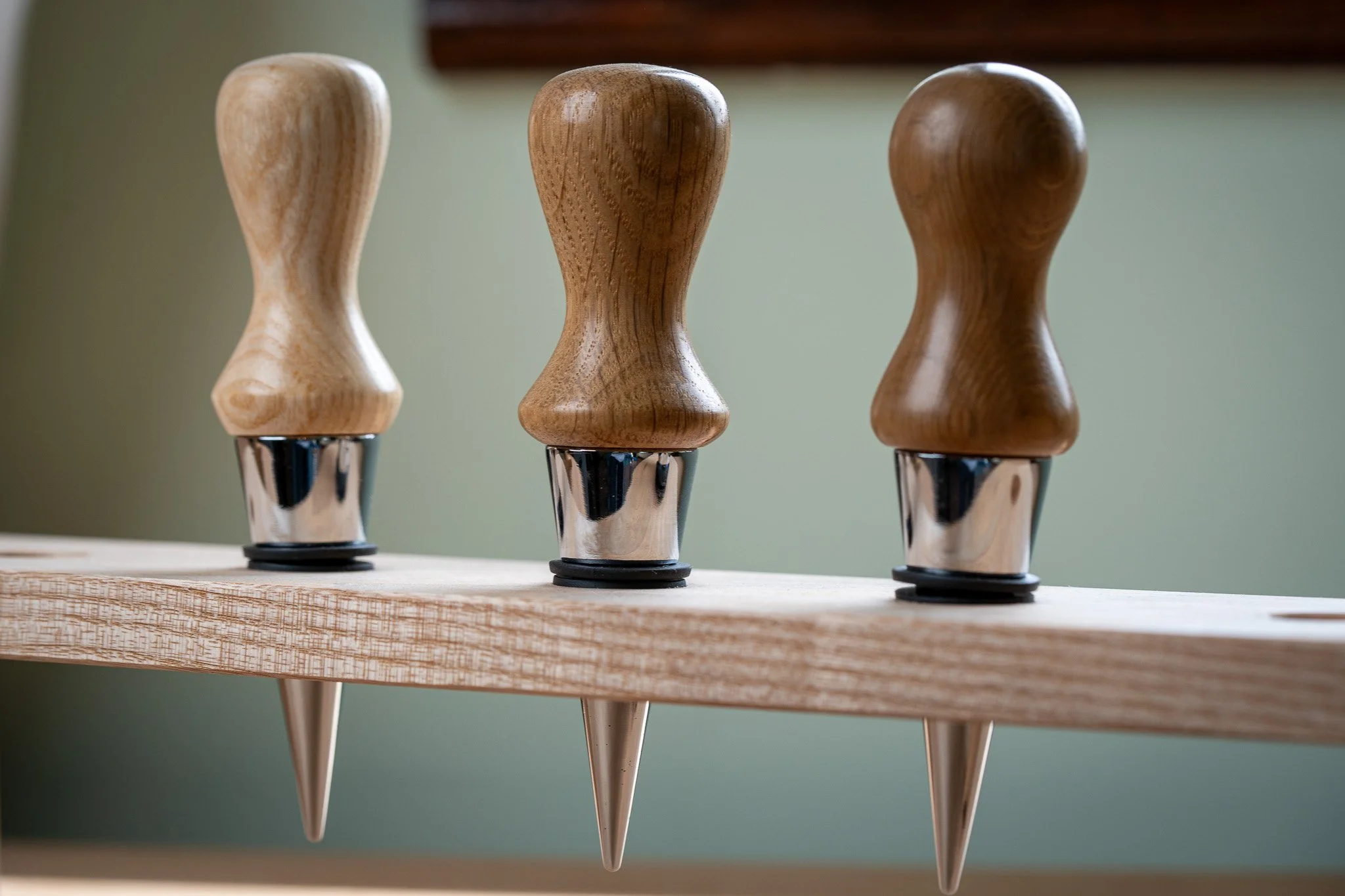 Three wooden-handled tools with metal tips, placed upright on a wooden surface.