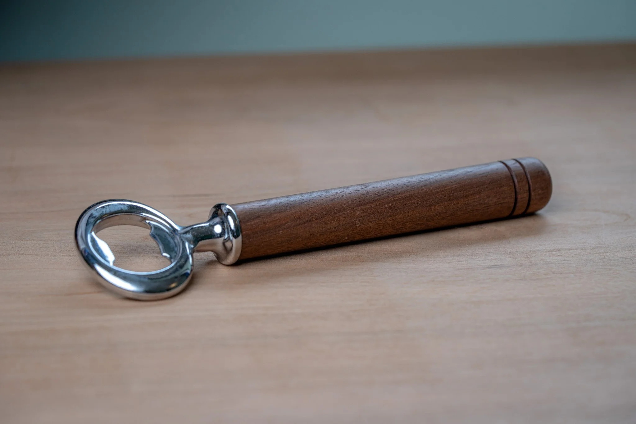 A corkscrew with a wooden handle and metal spiral lying on a wooden surface.