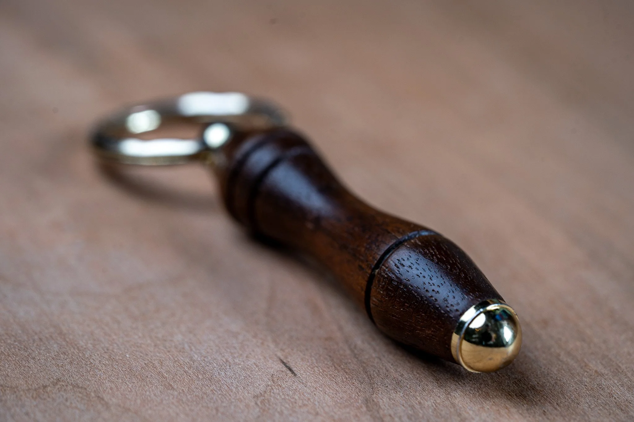 Close-up of a fountain pen with a wooden body and metallic accents on a beige surface.
