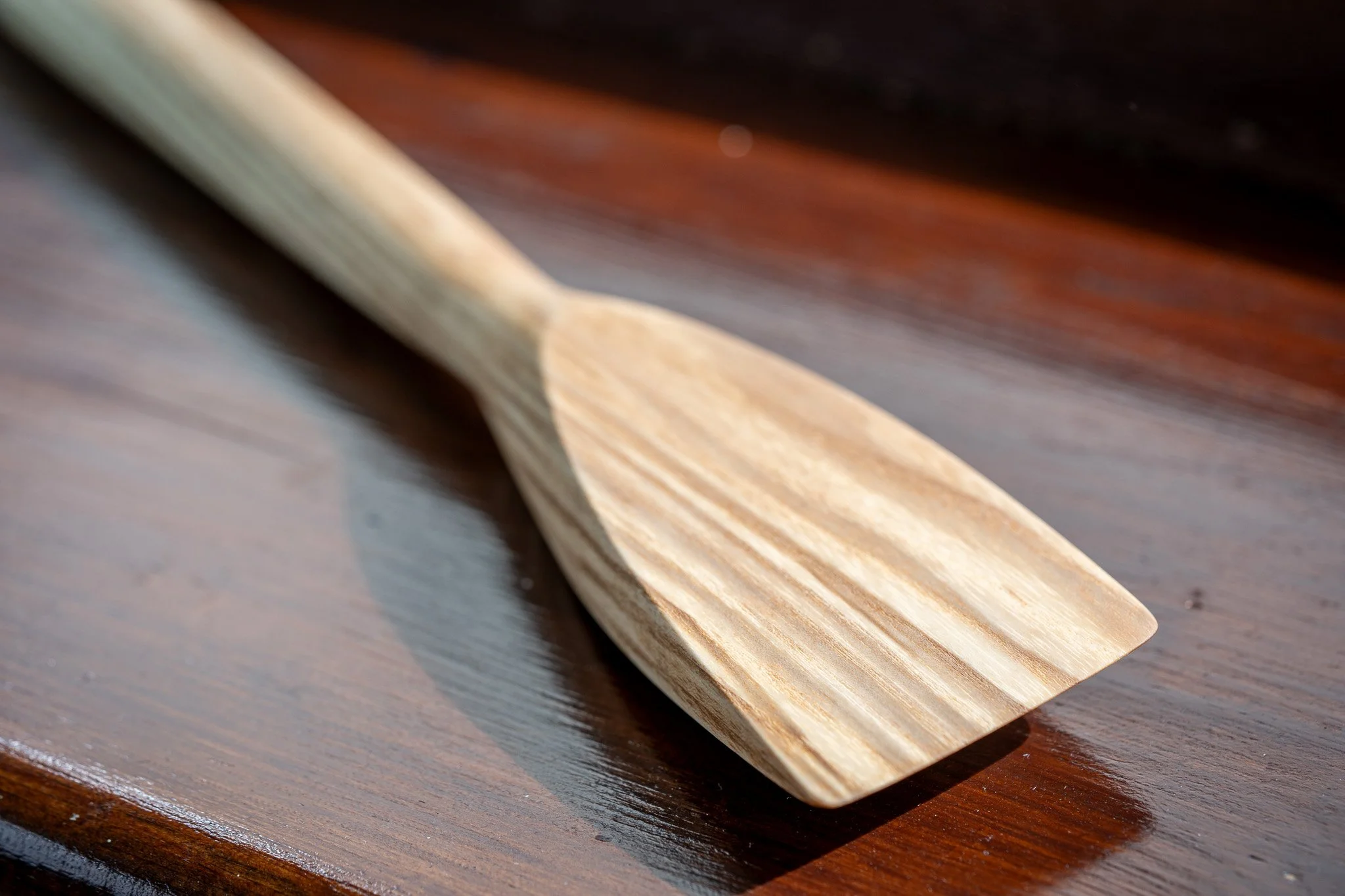 Close-up of a piece of light-colored wood on a dark polished wooden surface.
