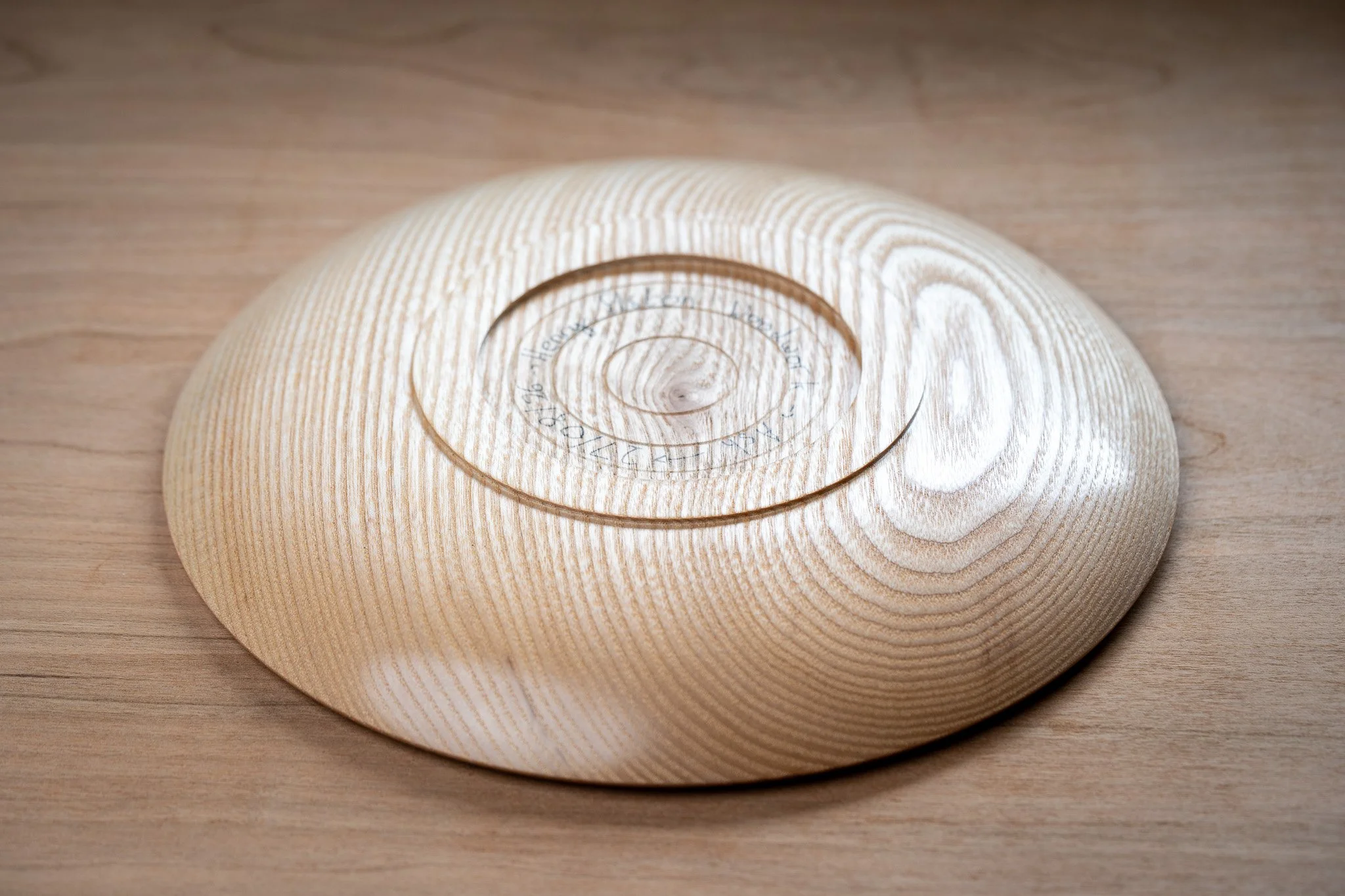 A wooden spiral lattice on a round wooden base on a wooden surface.