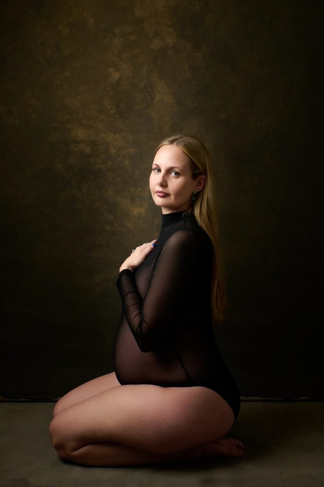 Maternity photography in Austin, Texas by Breeanna Rose Photography. Solo portrait kneeling in a black bodysuit.