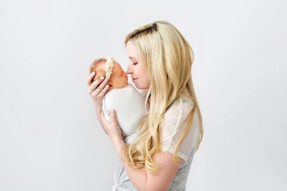 Newborn photography in Austin, Texas by Breeanna Rose Photography. Mom holding her baby up, gazing at her.