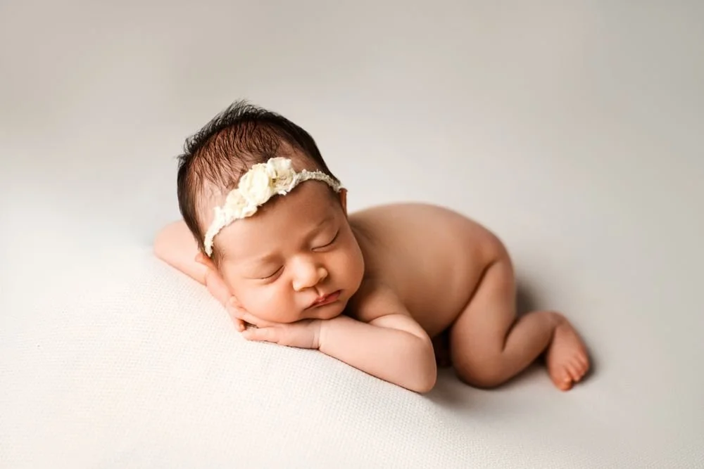 Newborn photography in Austin, Texas by Breeanna Rose Photography. Sleeping newborn with a cream floral headband.