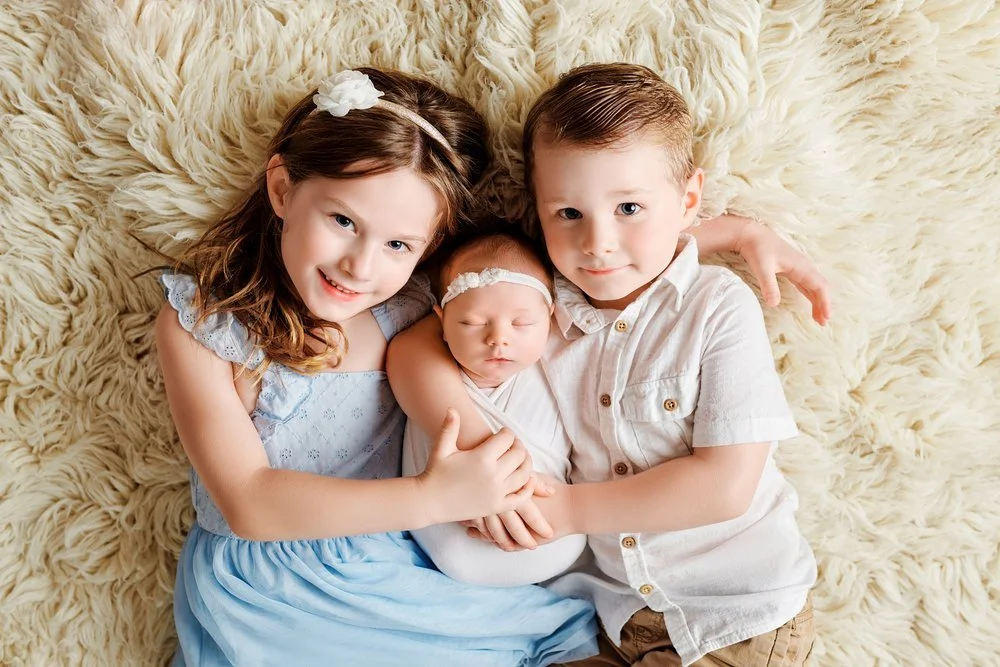 Newborn photography in Austin, Texas by Breeanna Rose Photography. Siblings on rug with newborn.