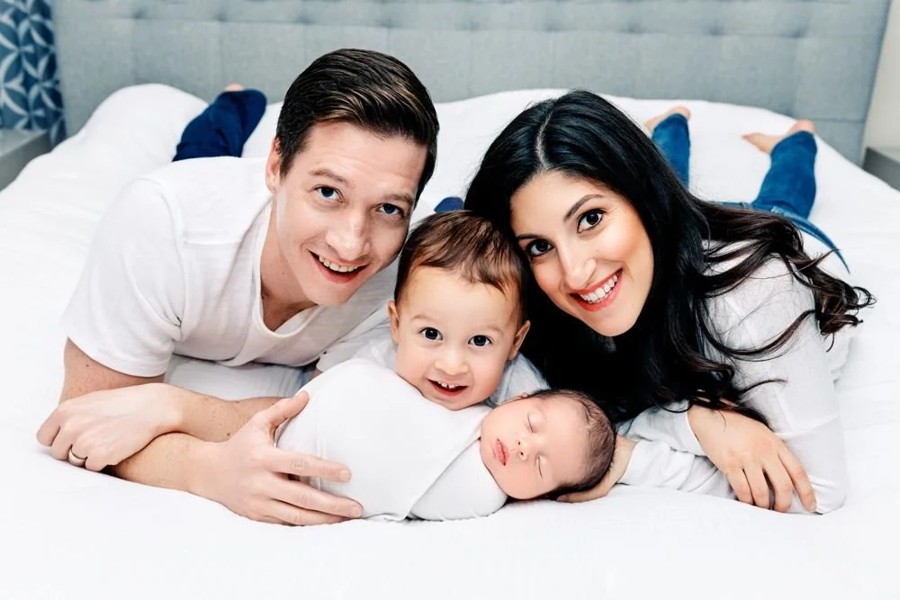 Newborn photography in Austin, Texas by Breeanna Rose Photography. Family on the bed, laughing.