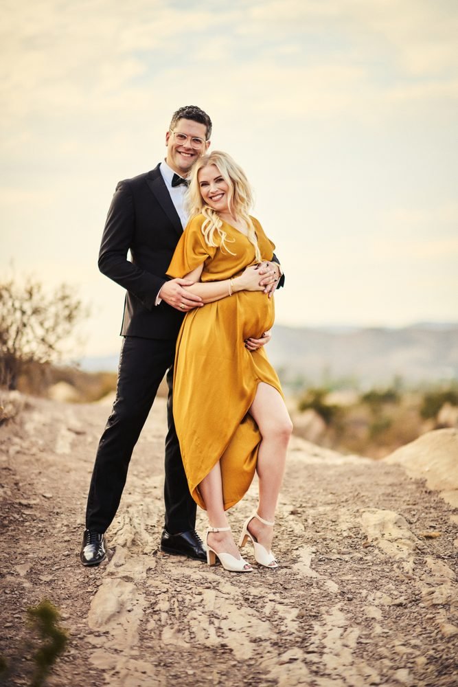 Maternity photography in Austin, Texas by Breeanna Rose Photography. Couple portrait, mustard gown, partner behind her, rocky hills.