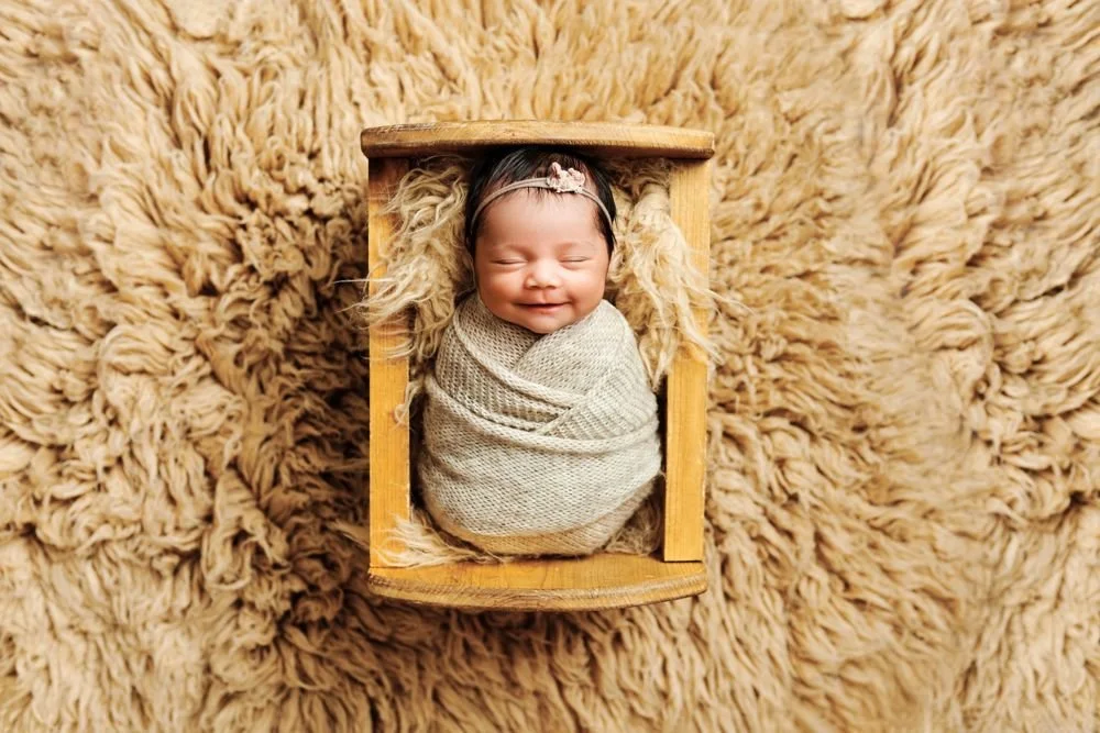Newborn photography in Austin, Texas by Breeanna Rose Photography. Newborn in a wooden box on fur, seen from above.