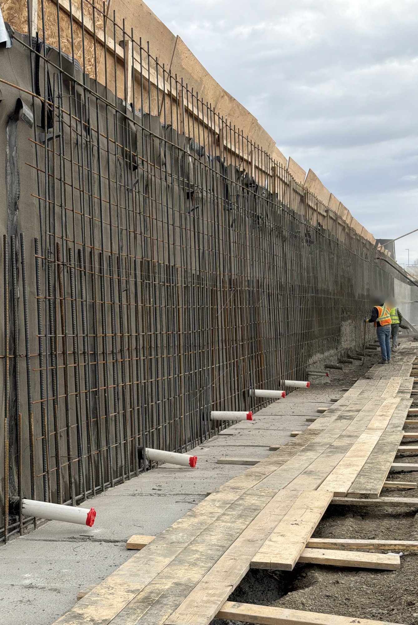 ong run of rebar along a shored excavation wall in Regina, ready for shotcrete, with a plank walkway beside it