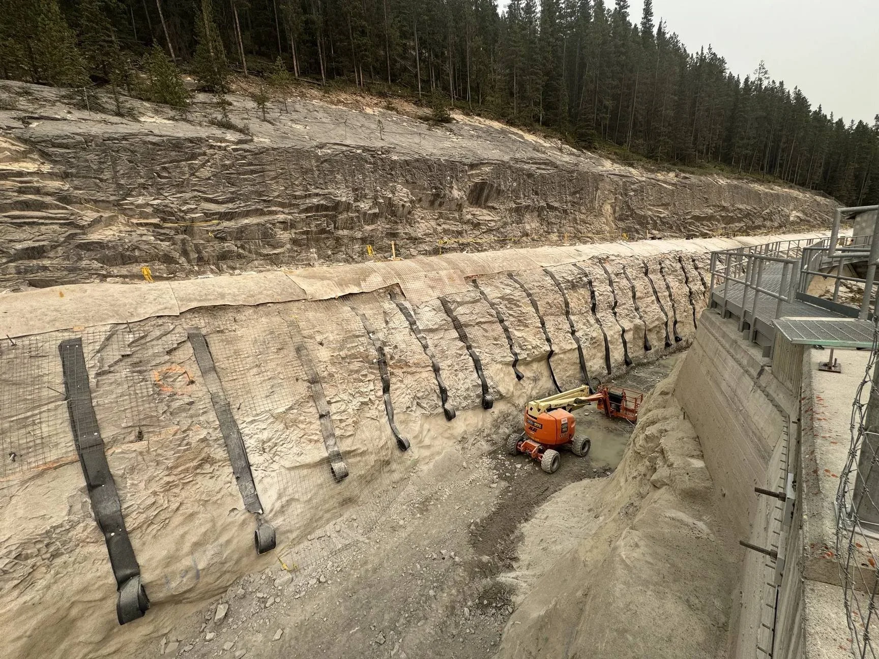 Retaining wall face on a rock cut with vertical strip drains and geotextile before shotcrete, Alberta