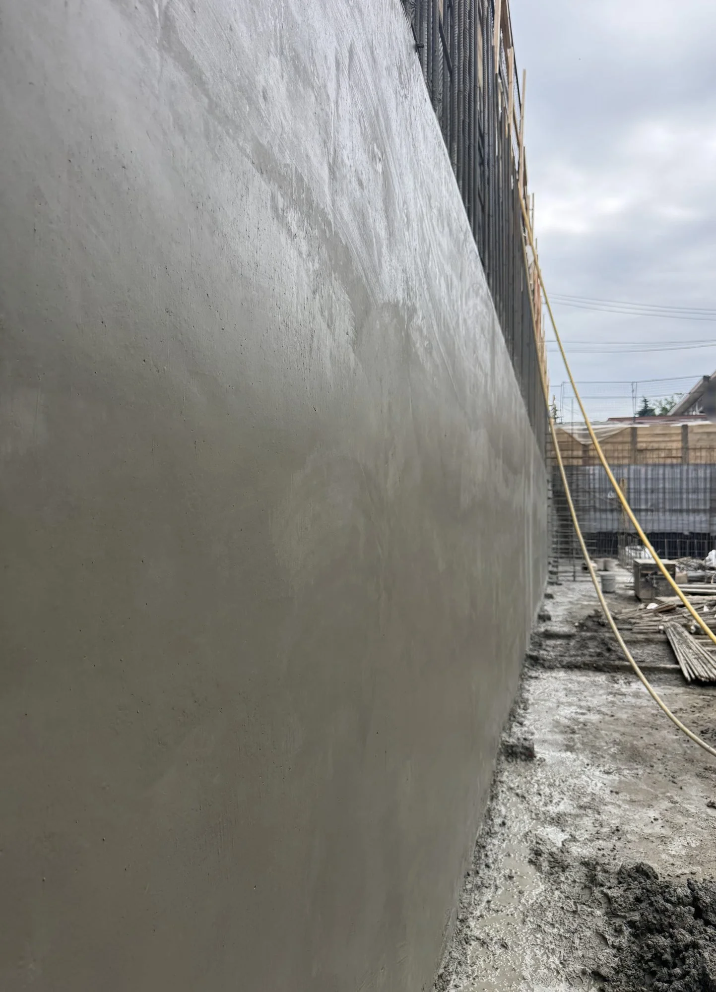 Long view down a finished structural shotcrete wall in an Edmonton excavation, rebar and shoring above