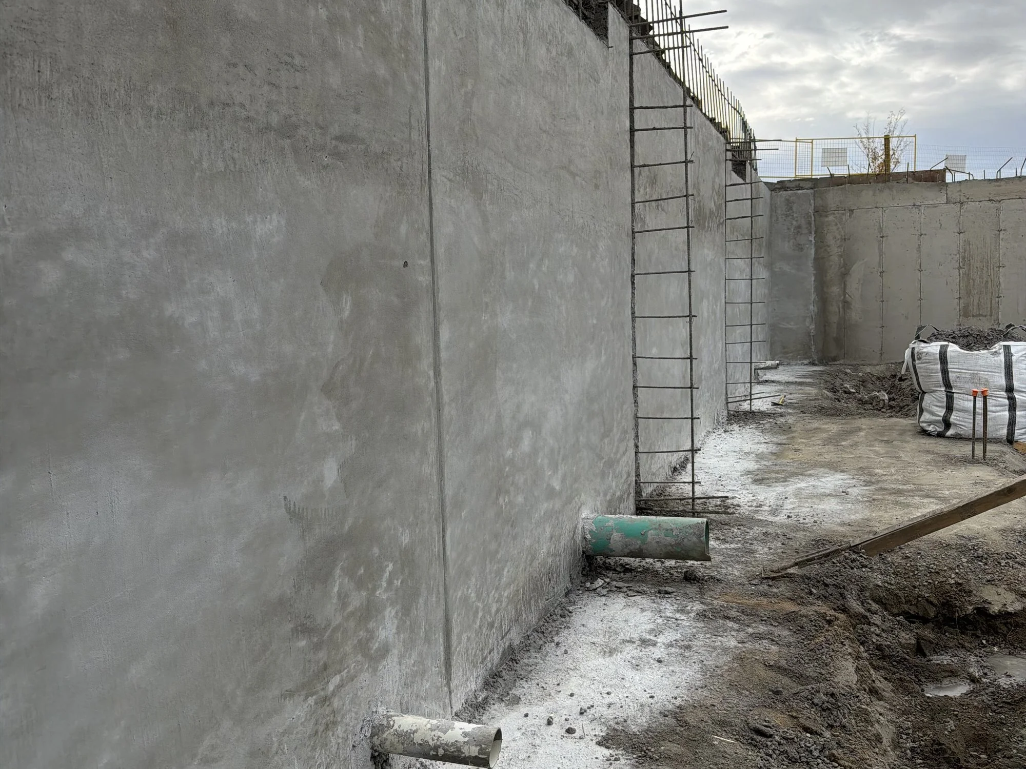 Finished shotcrete retaining wall on a shored excavation in Regina, SK, with rebar left out along the top