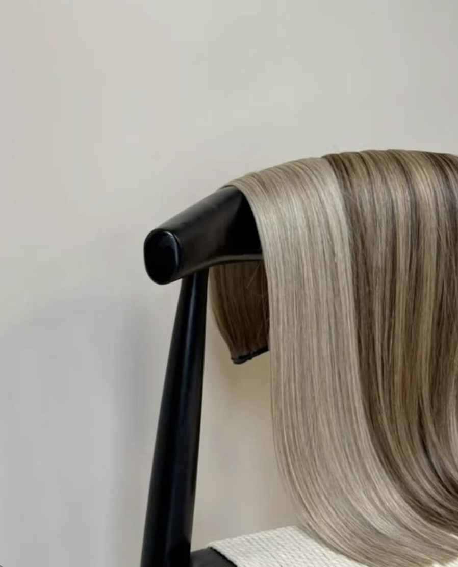 A hair modeling stand with long, straight, blonde hair on a black hair mannequin head.