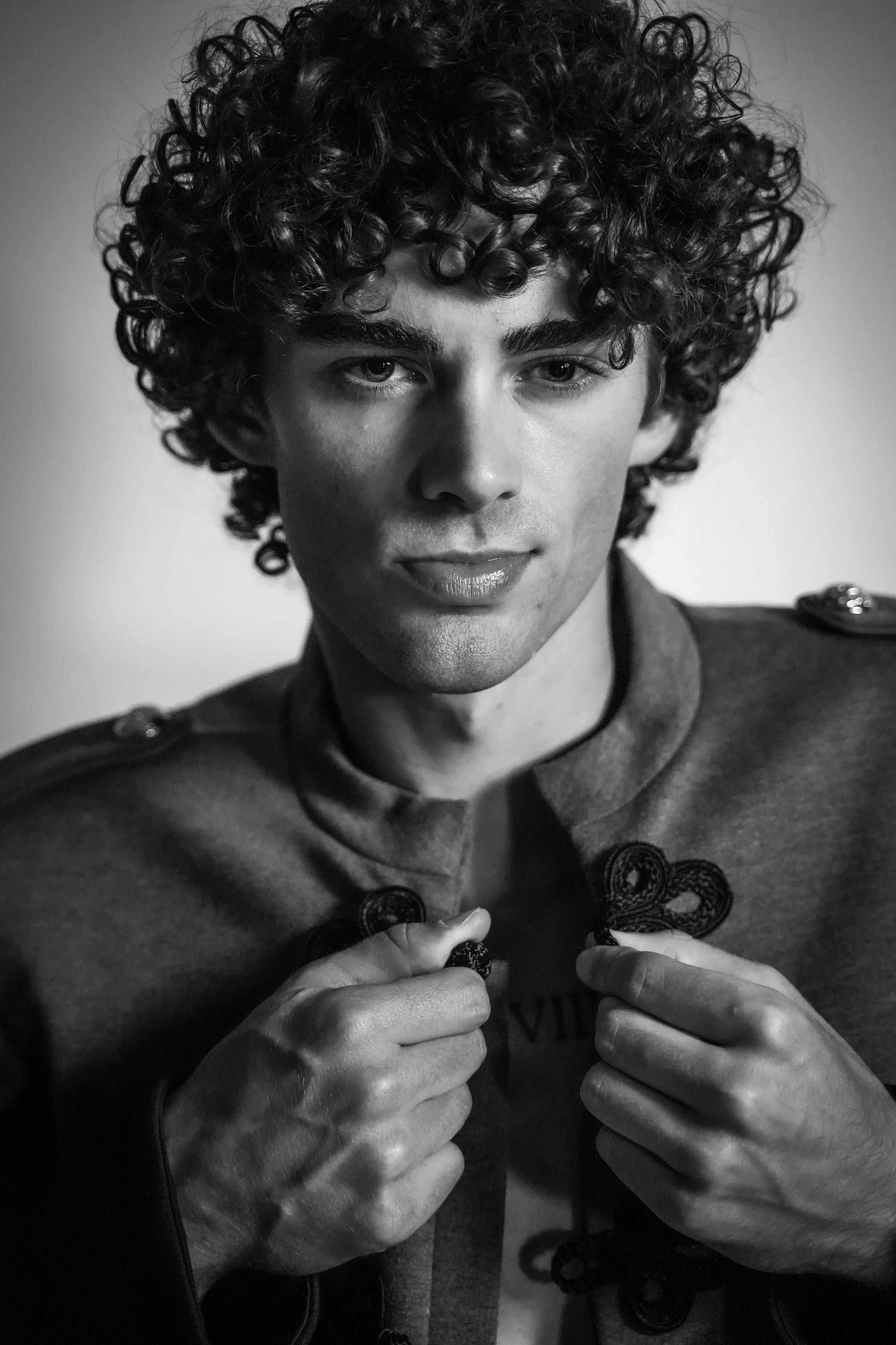 Maverick, male fashion model represented by Noirvelle Models, posing in a black-and-white editorial portrait wearing a detailed jacket.