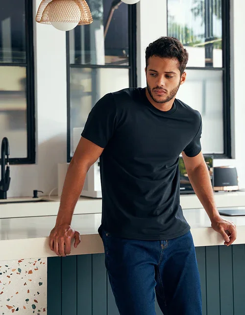 Bashir, male model represented by Noirvelle Models, wearing a black T-shirt and jeans in a modern lifestyle setting.
