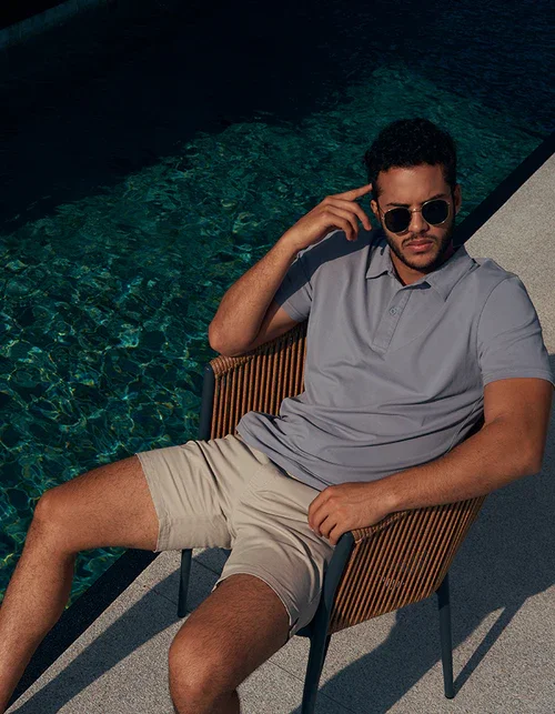 Bashir, male model represented by Noirvelle Models, relaxing poolside in sunglasses and a casual polo shirt.

