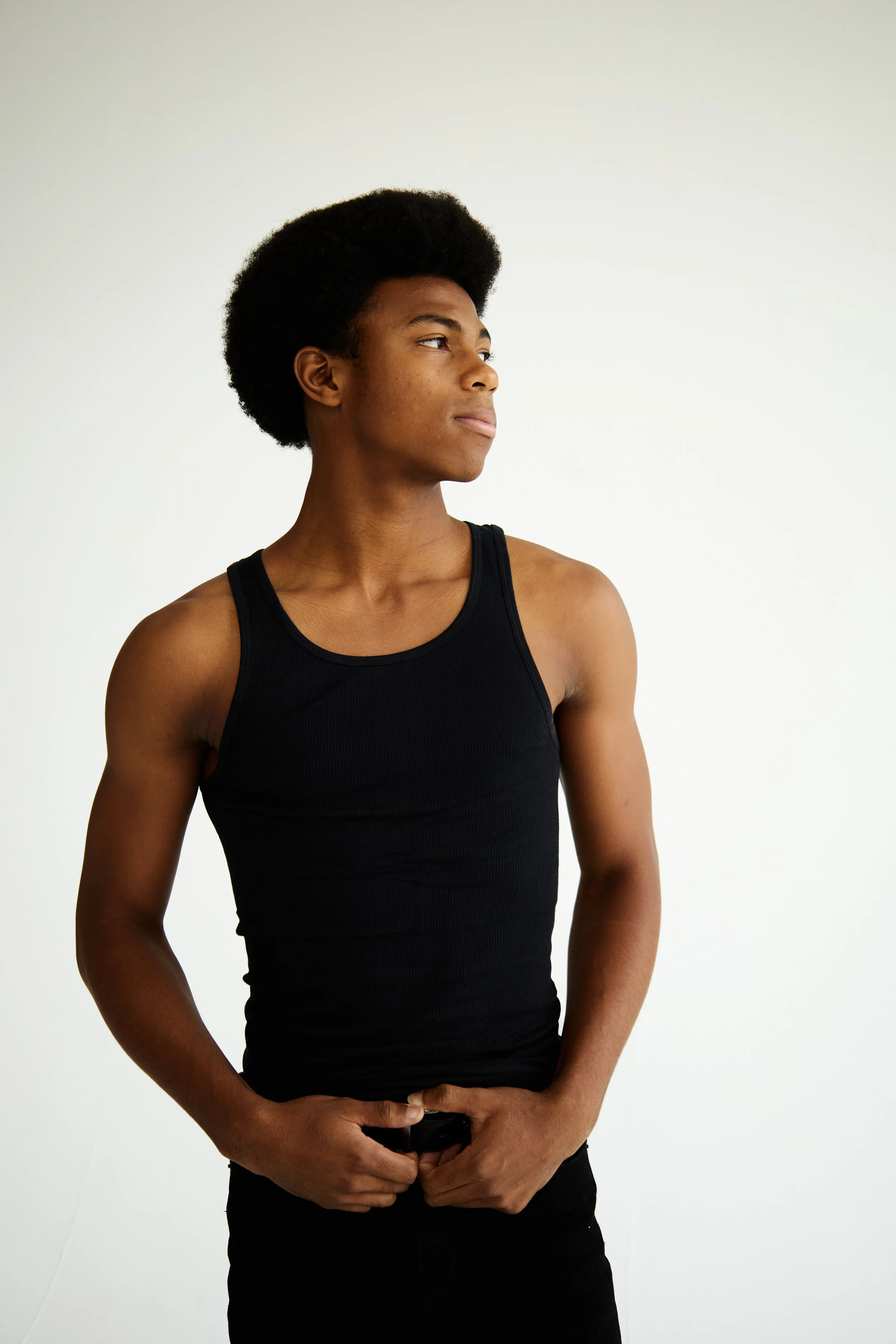 Jahvante, male fashion model represented by Noirvelle Models, standing in profile in an all-black outfit against a white studio background.
