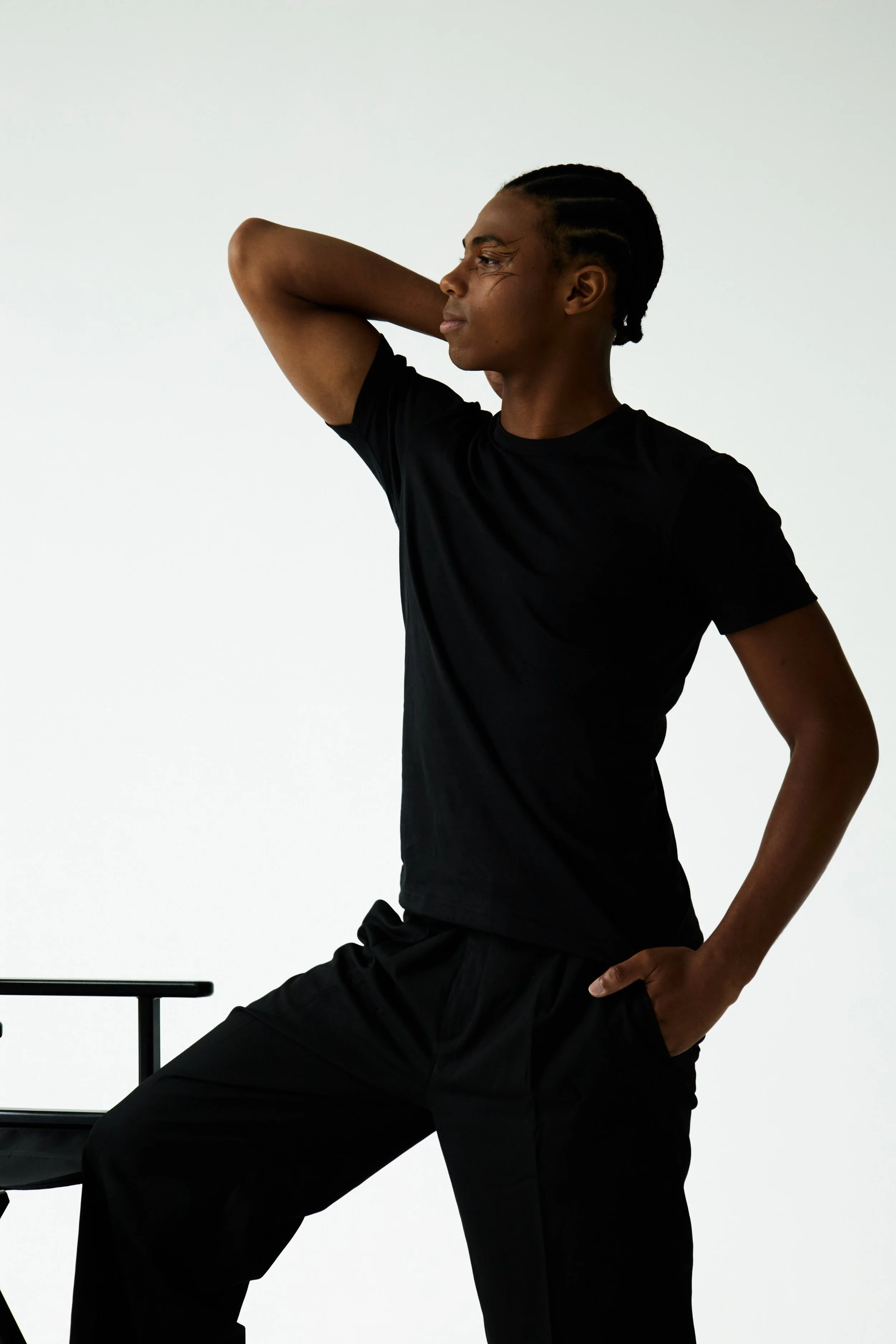 Jahvante, male fashion model represented by Noirvelle Models, posing in a black tank top and black pants against a white studio background.
