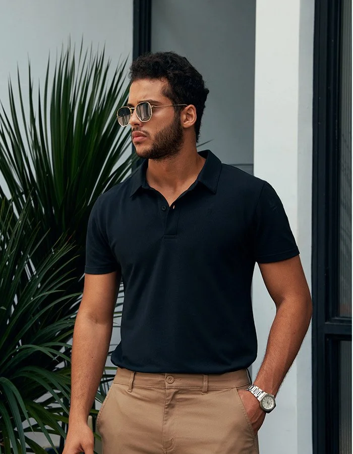  Bashir, male fashion model represented by Noirvelle Models, wearing sunglasses and a black polo shirt in an outdoor lifestyle portrait.
