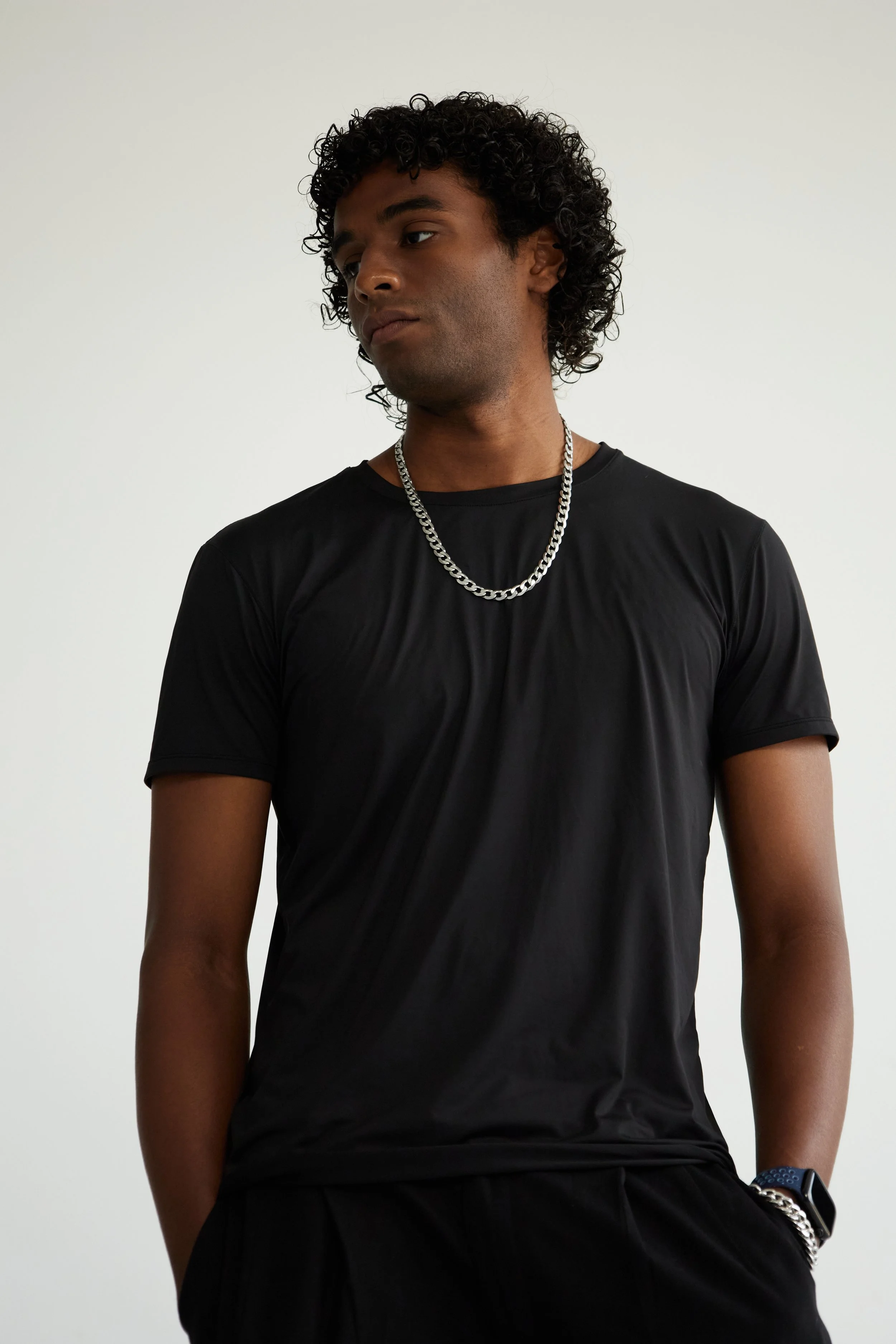 Xander, male fashion model represented by Noirvelle Models, standing in a black T-shirt against a white studio background.
