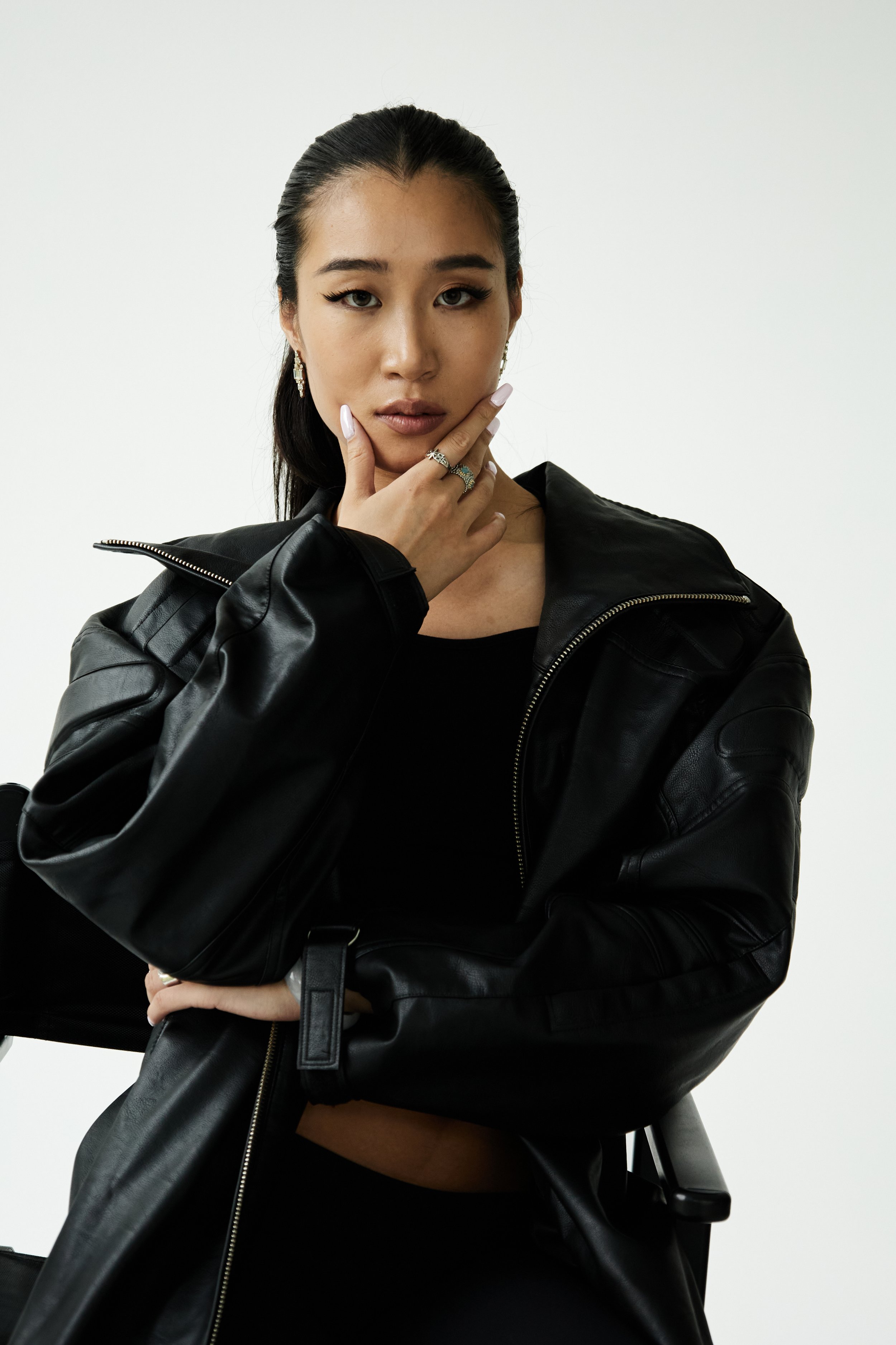 Joline, female fashion model represented by Noirvelle Models, seated in a black outfit during a studio fashion photoshoot.

