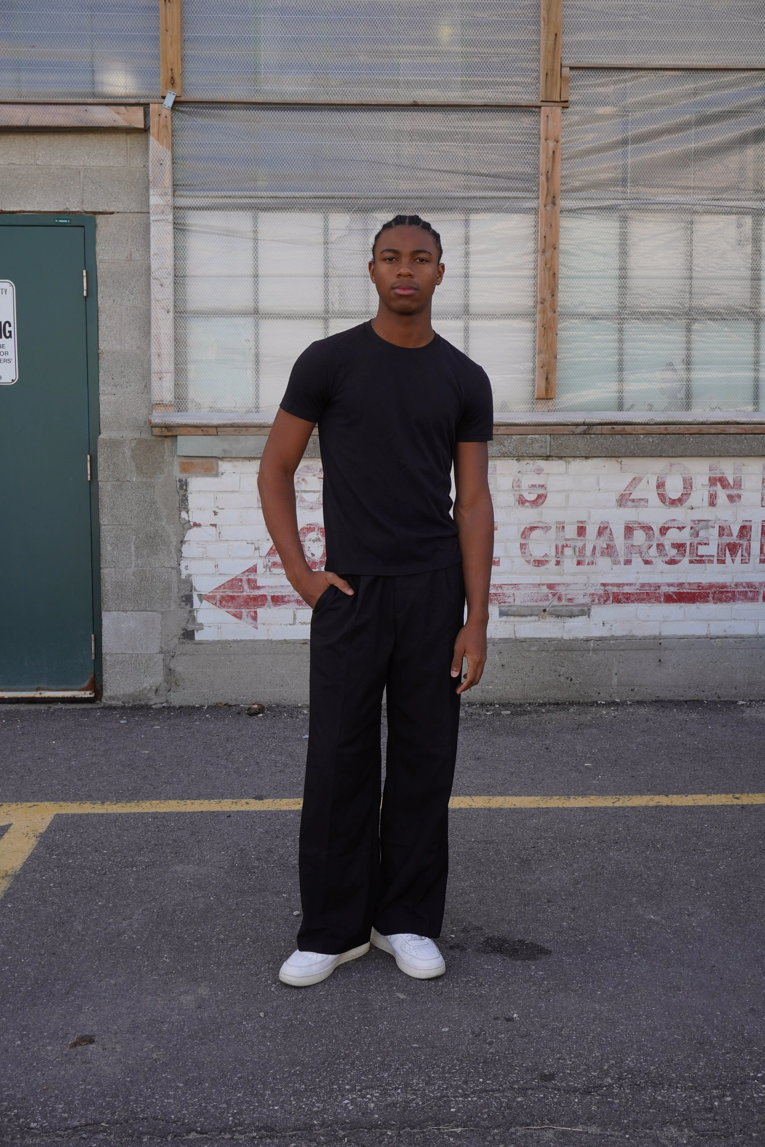  Jahvante, male fashion model represented by Noirvelle Models, full-length outdoor portrait in a black outfit.