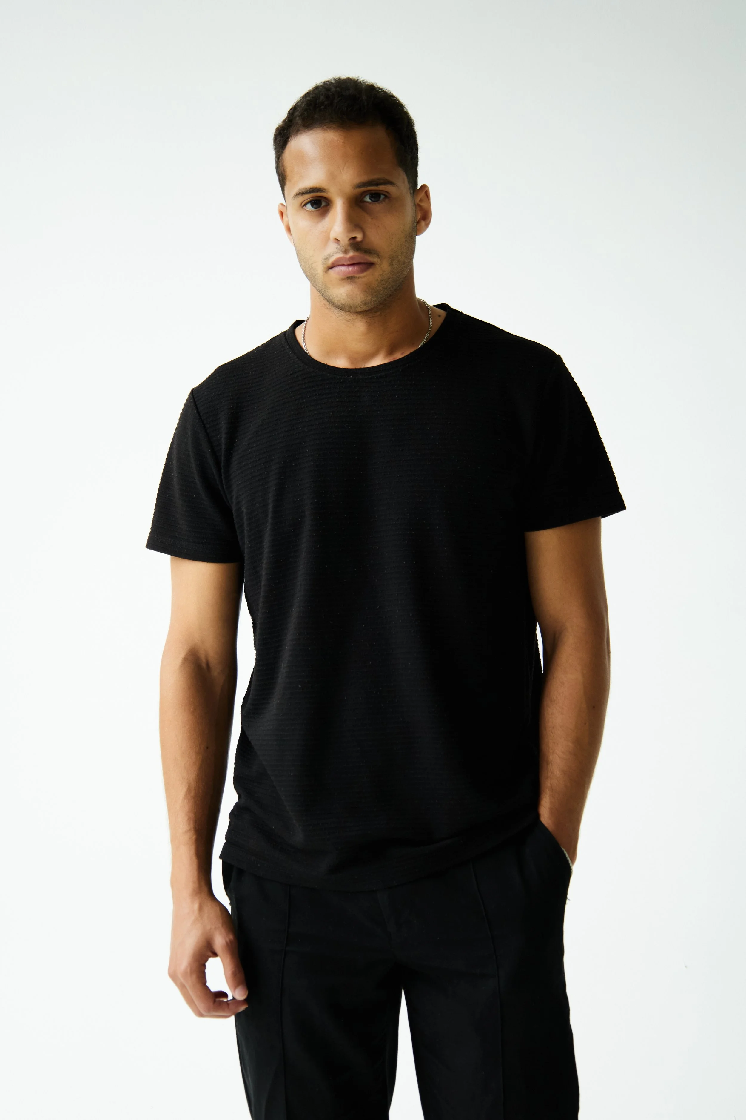 Bashir, male fashion model represented by Noirvelle Models, standing in an all-black outfit during a clean studio model test.