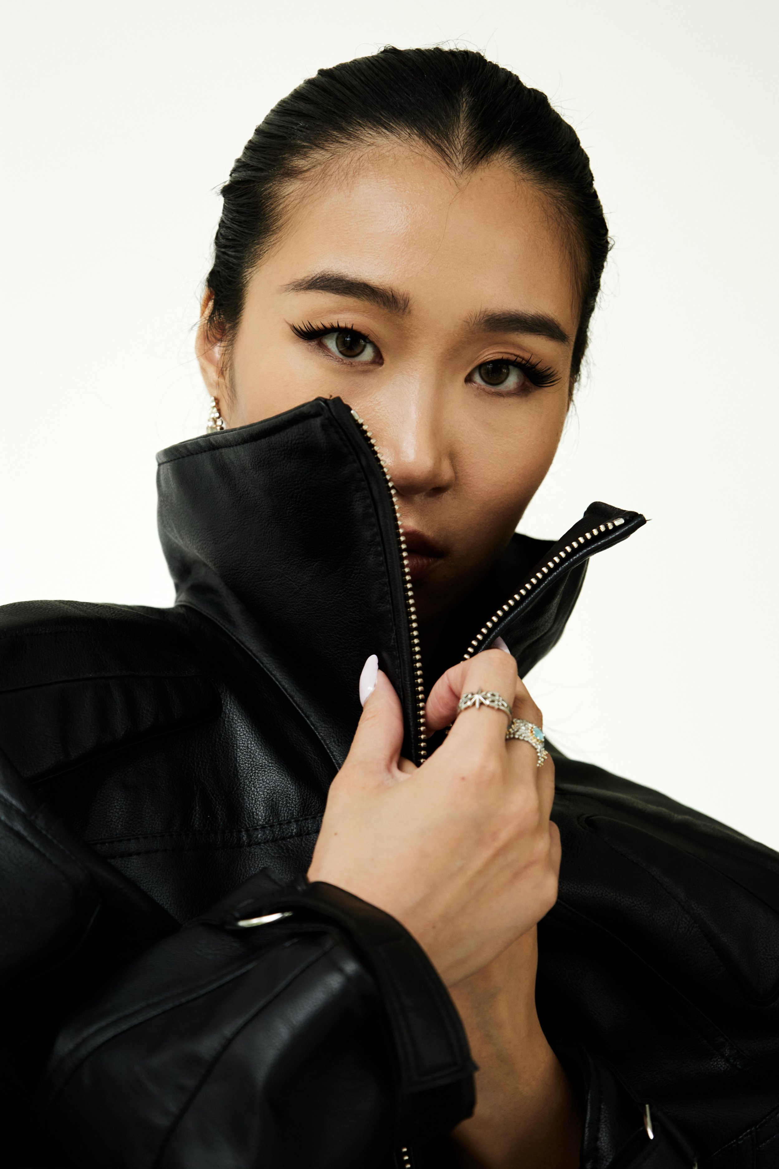 Joline, female fashion model represented by Noirvelle Models, close-up editorial portrait in a black leather jacket against a white studio background.