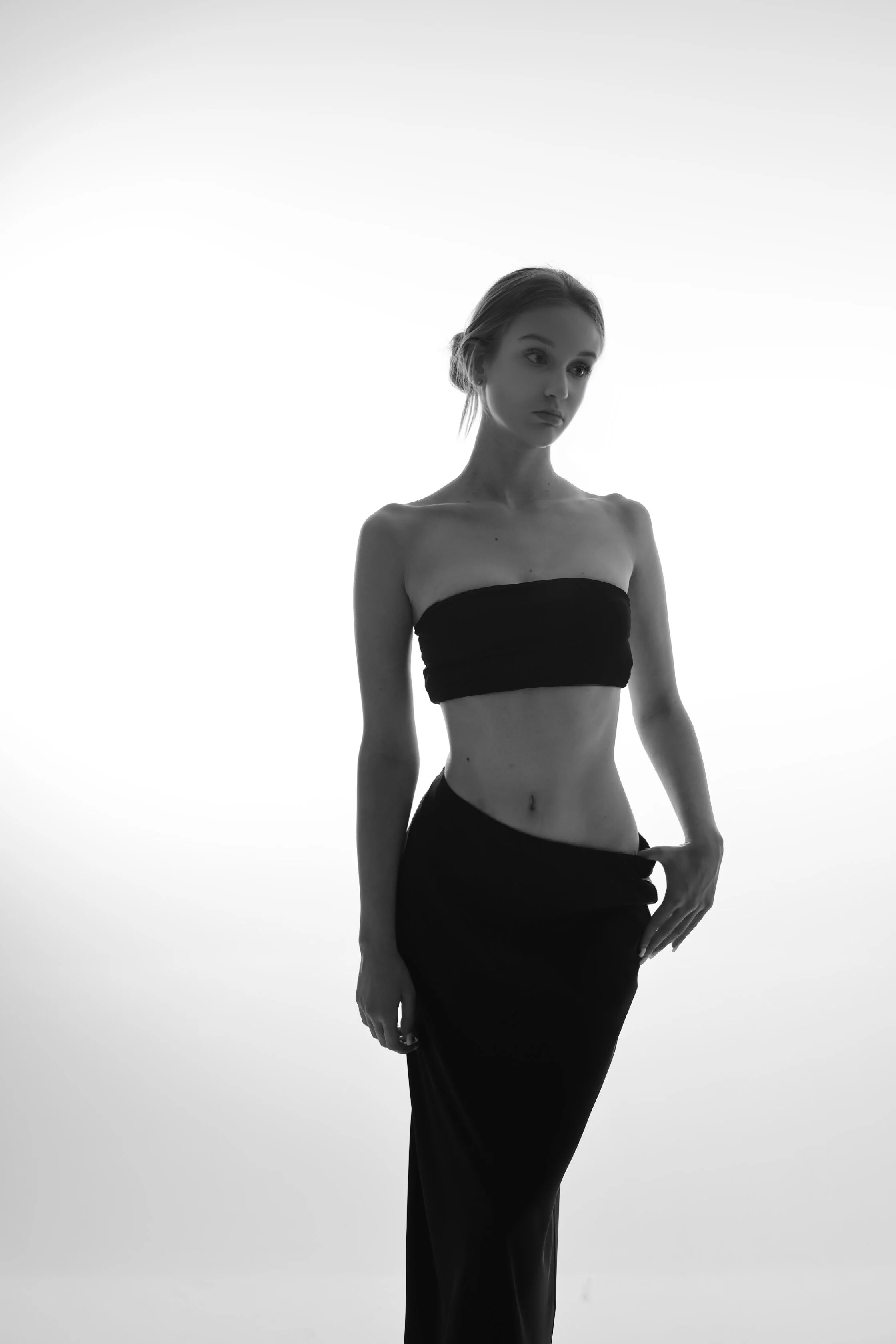 Victoria, female fashion model represented by Noirvelle Models, photographed in black and white wearing a black top and long skirt.
