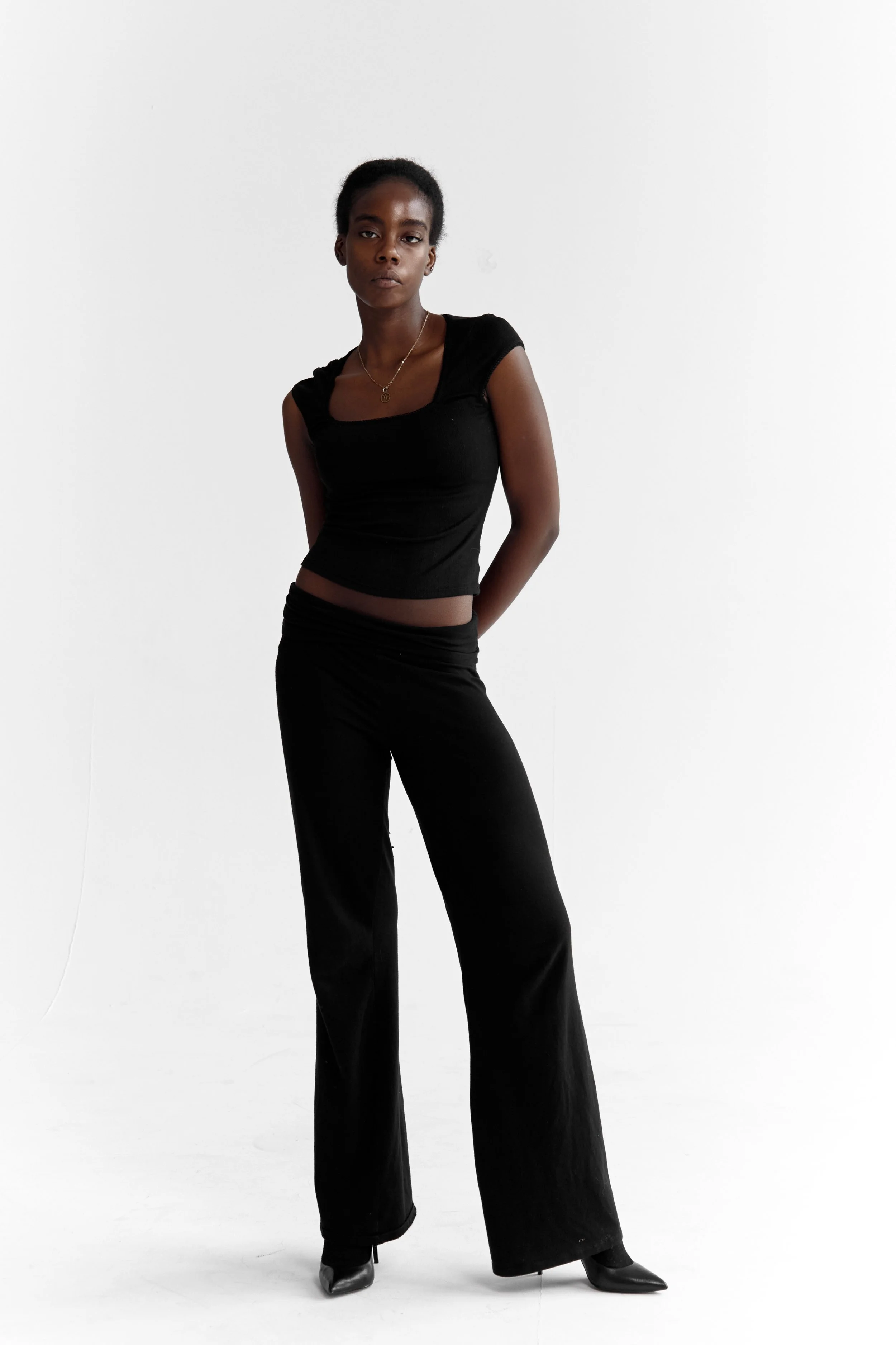 Daisy, female fashion model represented by Noirvelle Models, wearing a black sleeveless top and wide-leg pants in a studio portrait.

