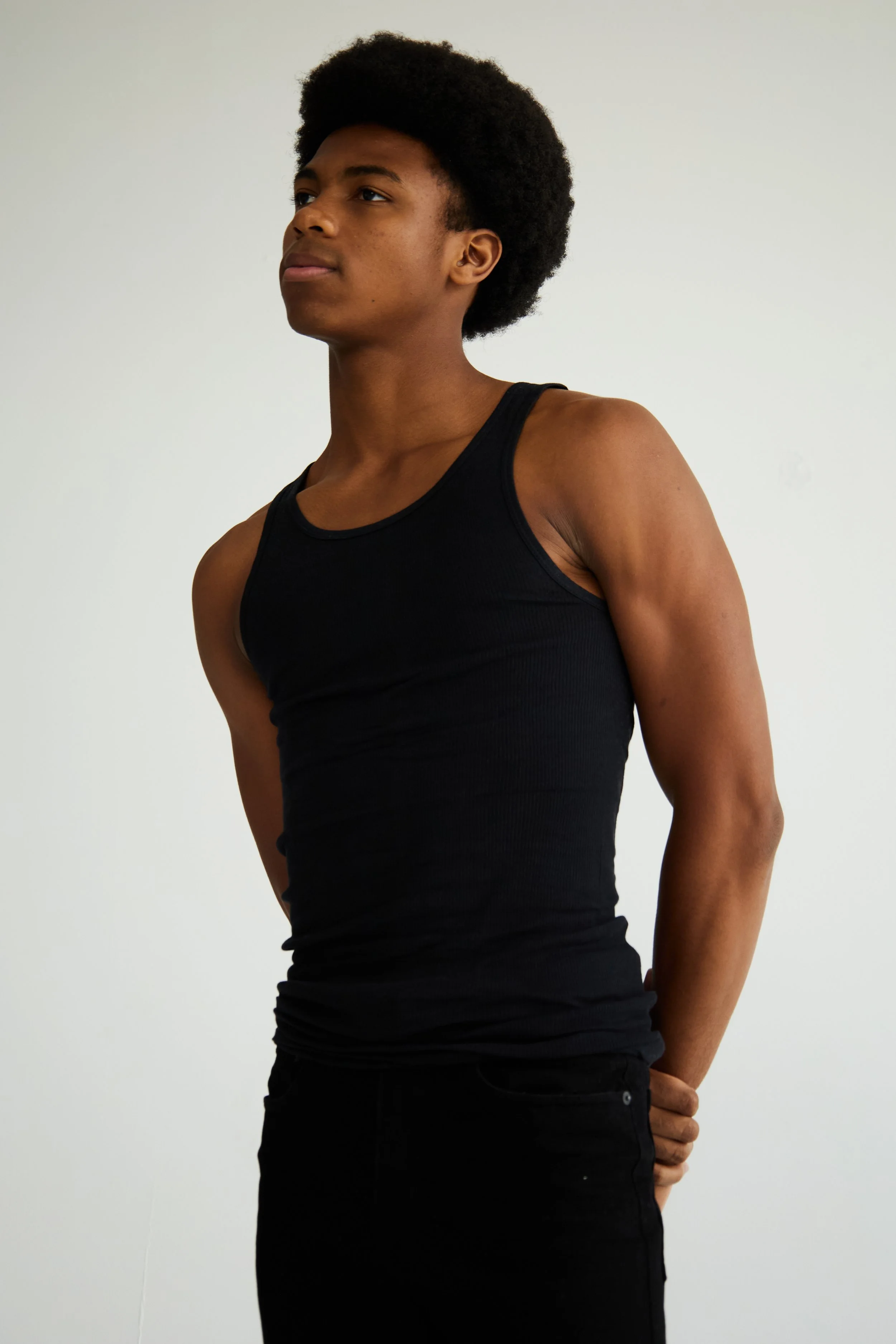Jahvante, male fashion model represented by Noirvelle Models, editorial portrait in a black sleeveless top against a white studio background.