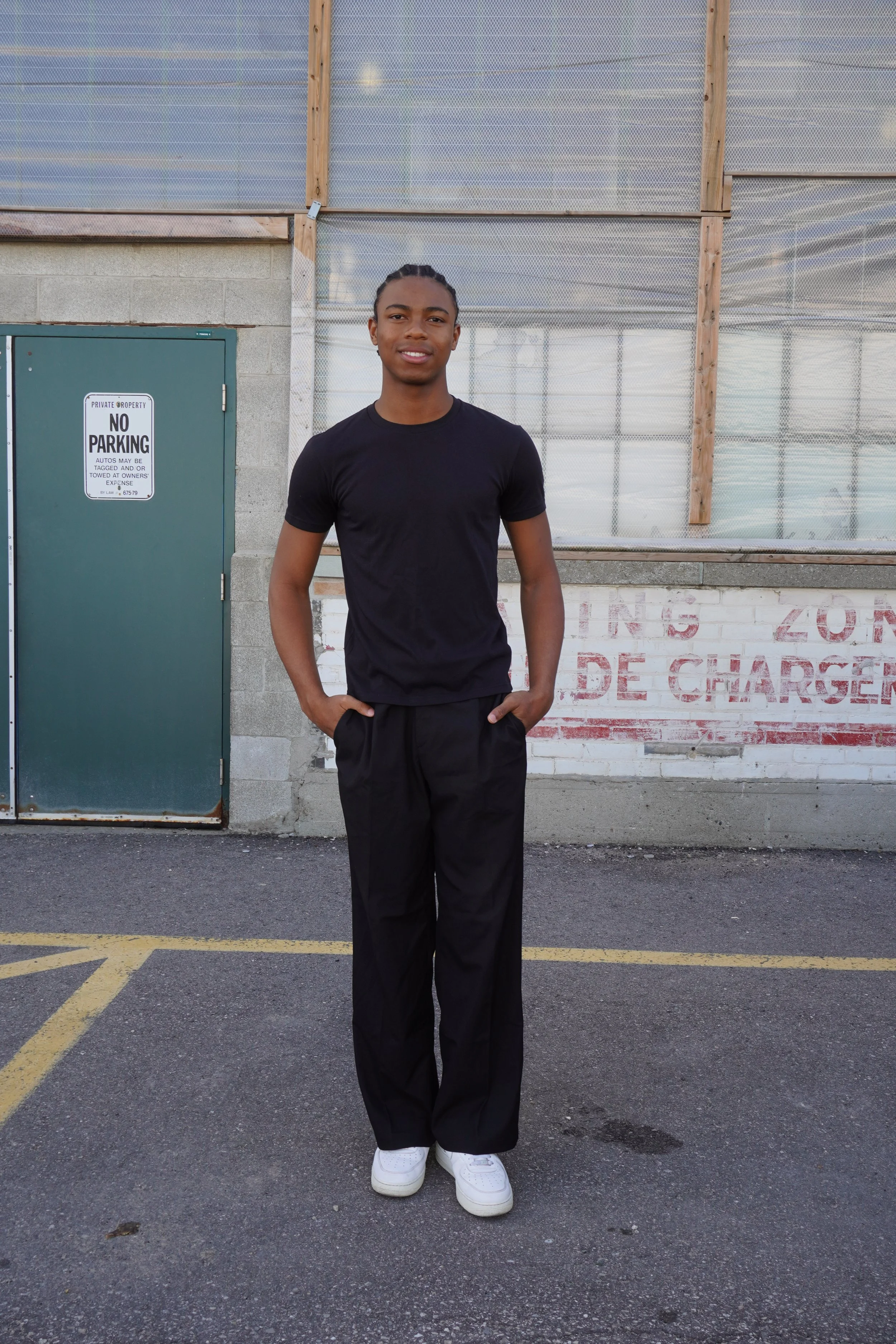  Jahvante, male fashion model represented by Noirvelle Models, standing outdoors in an all-black outfit during a fashion photoshoot.
