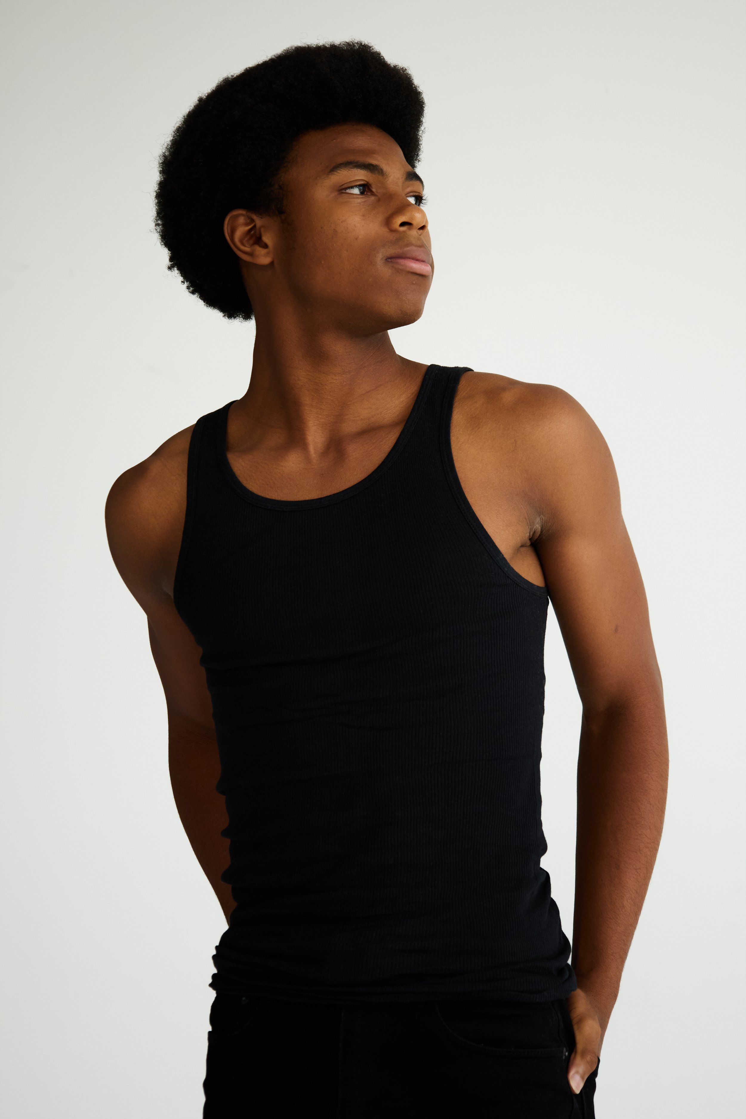 Jahvante, male fashion model represented by Noirvelle Models, posing in a black tank top against a white studio background.
