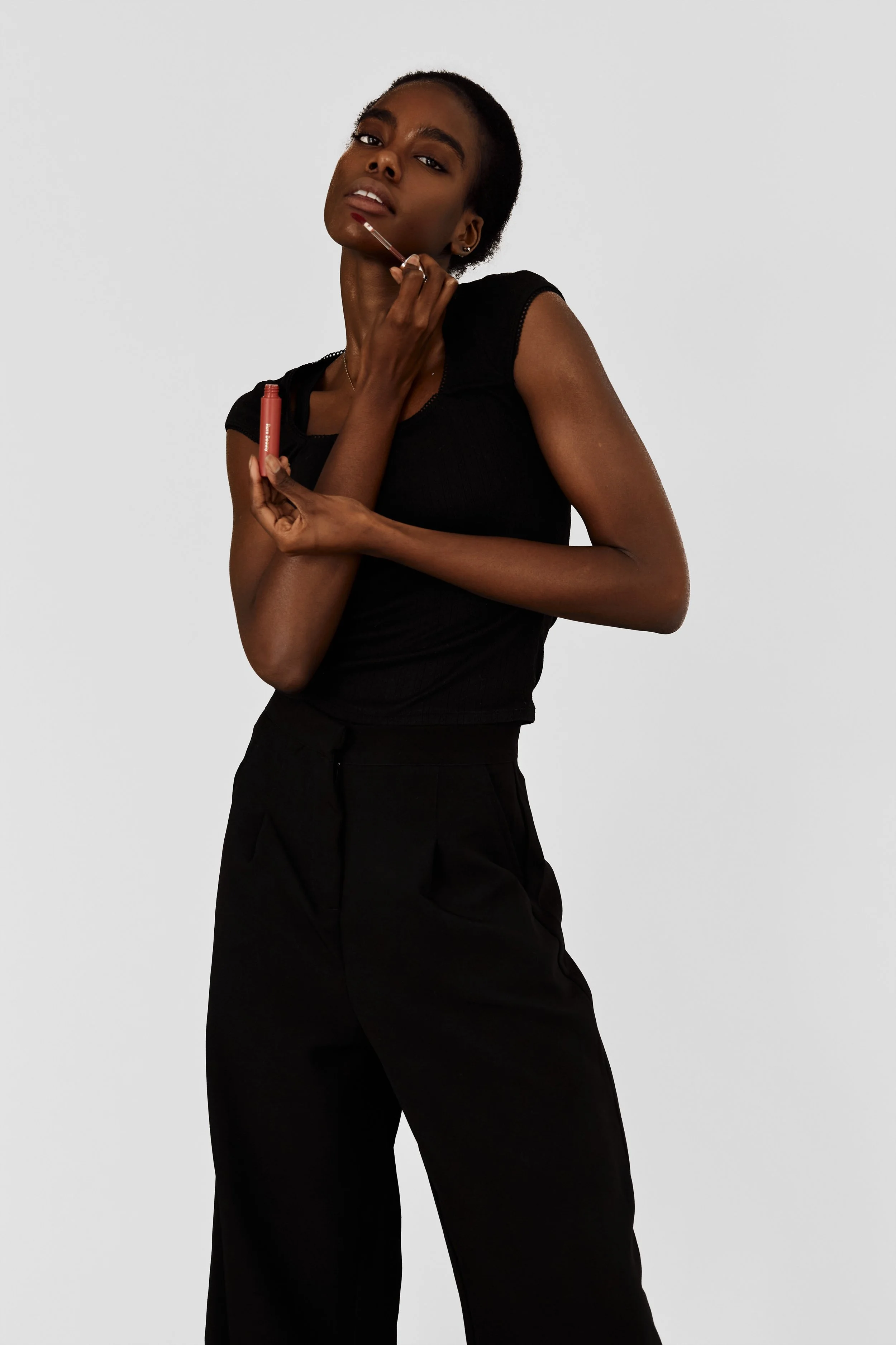 Daisy — female fashion model represented by Noirvelle Models, applying lipstick in a clean beauty editorial.