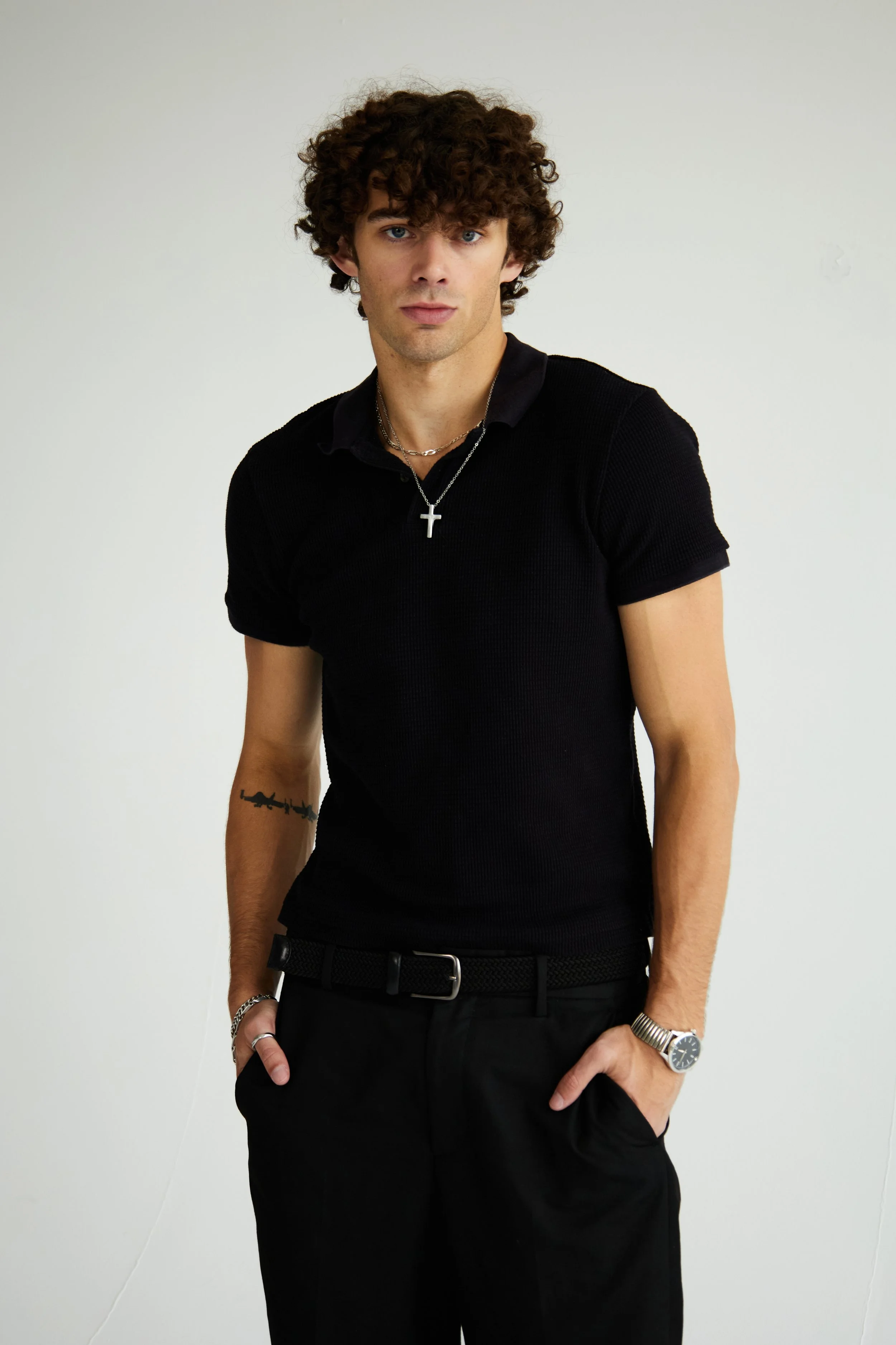 Maverick, male fashion model represented by Noirvelle Models, wearing an all-black look and silver jewelry against a white studio background.
