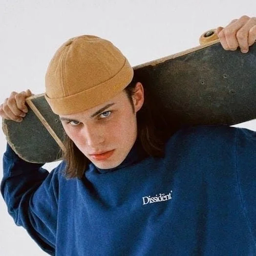 Konstantin Churakov — male fashion model represented by Noirvelle Models, styled in a casual streetwear look with a cap and skateboard.
