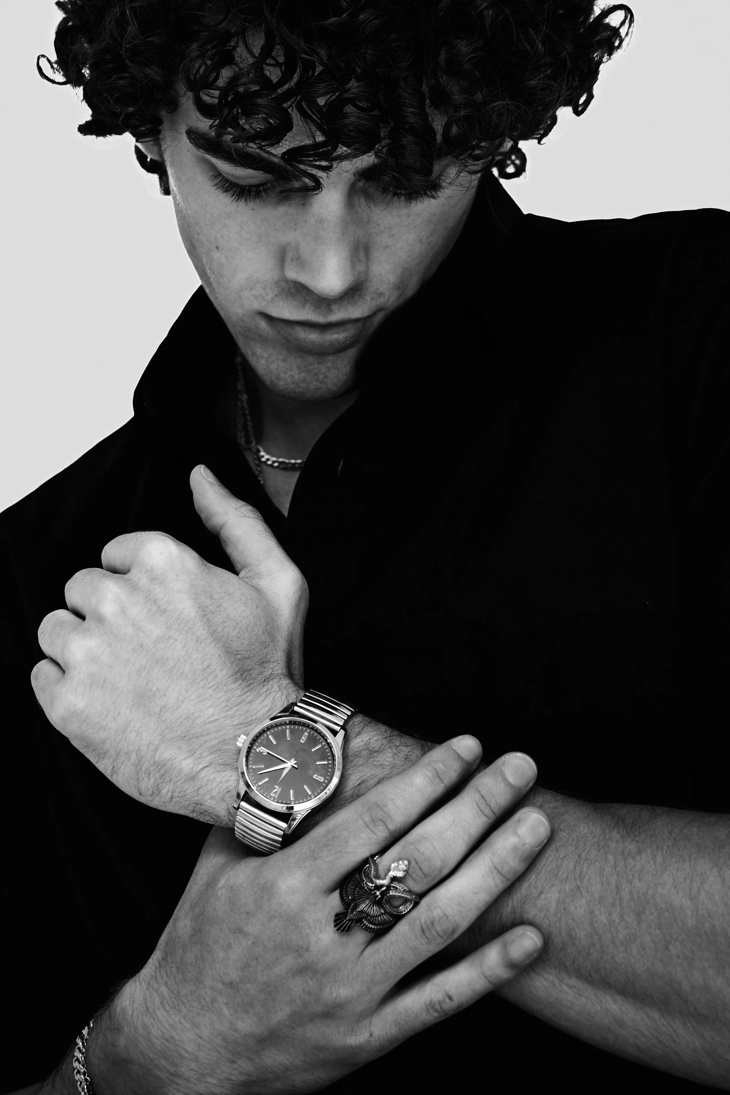 Maverick, male fashion model represented by Noirvelle Models, posing in a black-and-white editorial portrait with silver jewelry.
