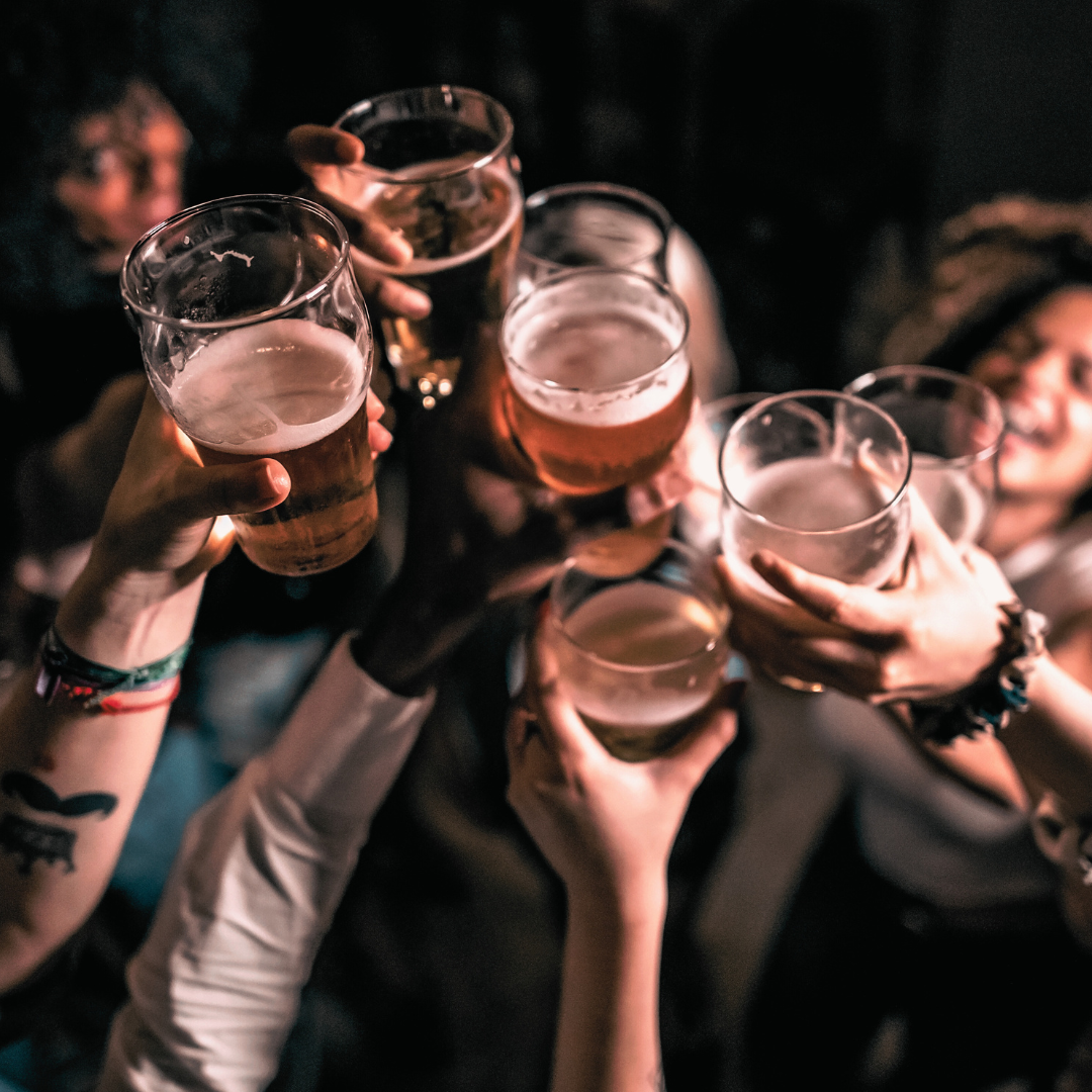Group of people raising glasses of beer in a toast at a party or celebration.