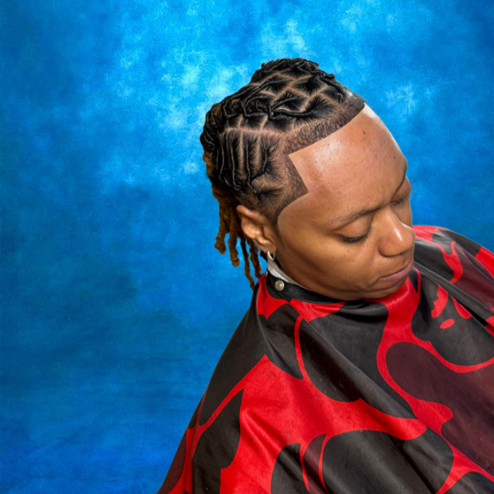 Woman with a new intricate hairstyle featuring cornrows and a shaved side, wearing a black and red salon cape, against a blue textured background.