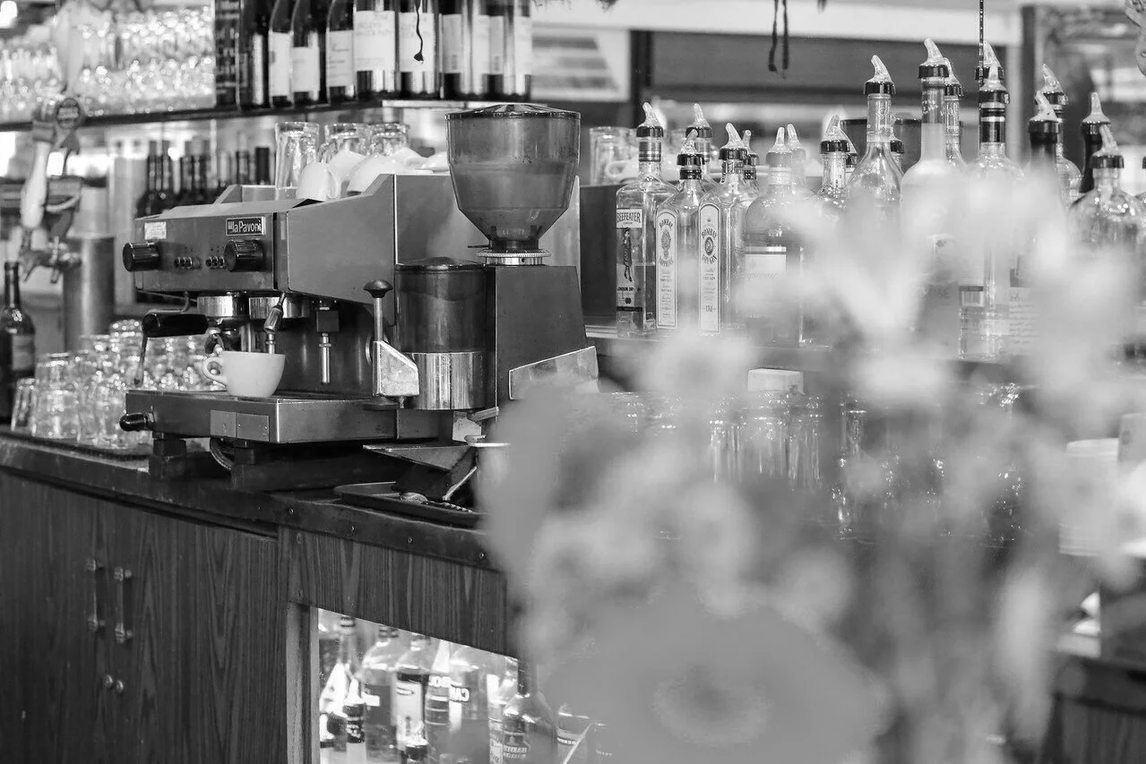Coffee machine on a bar counter with liquor bottles in the background