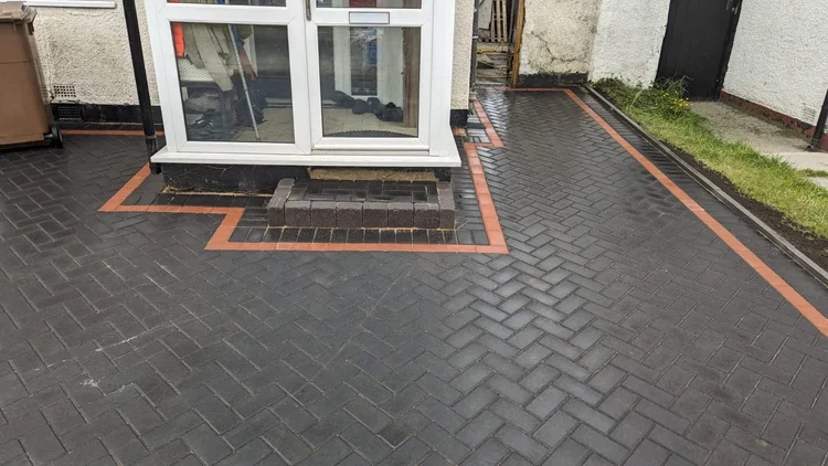Herringbone driveway with a red border wrapping round the porch