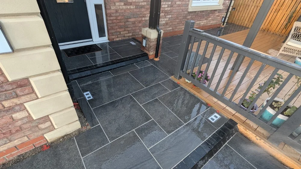 Dark porcelain patio beside a raised deck