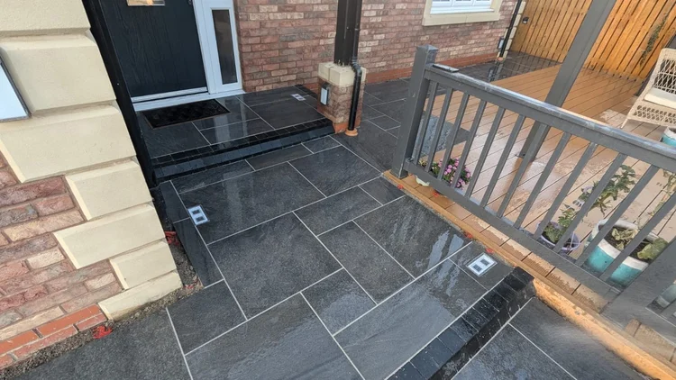 Dark porcelain patio beside a raised deck