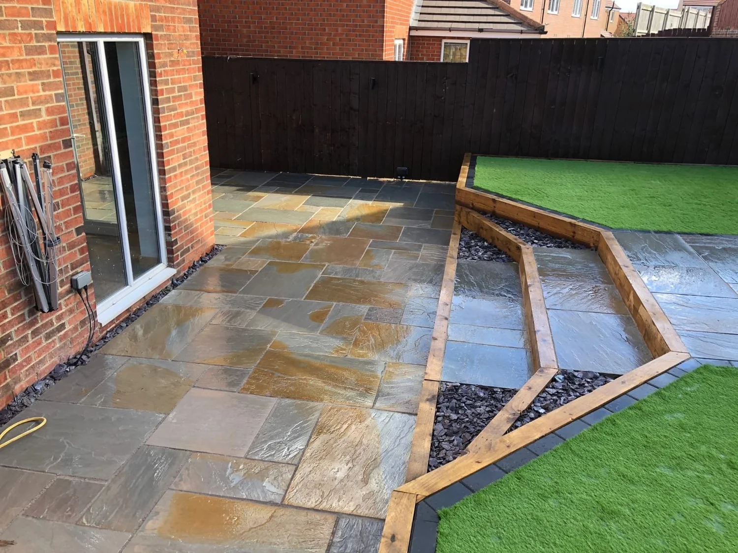 Sandstone patio with angled beds and artificial lawn
