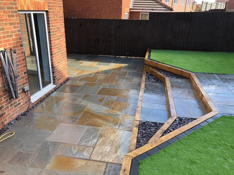 Sandstone patio with angled beds and artificial lawn