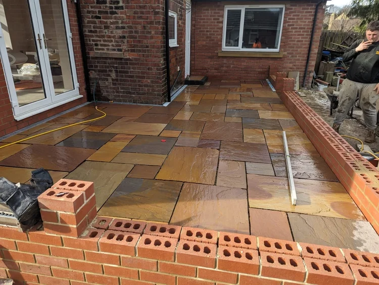 Rainbow sandstone patio with a new brick wall under way