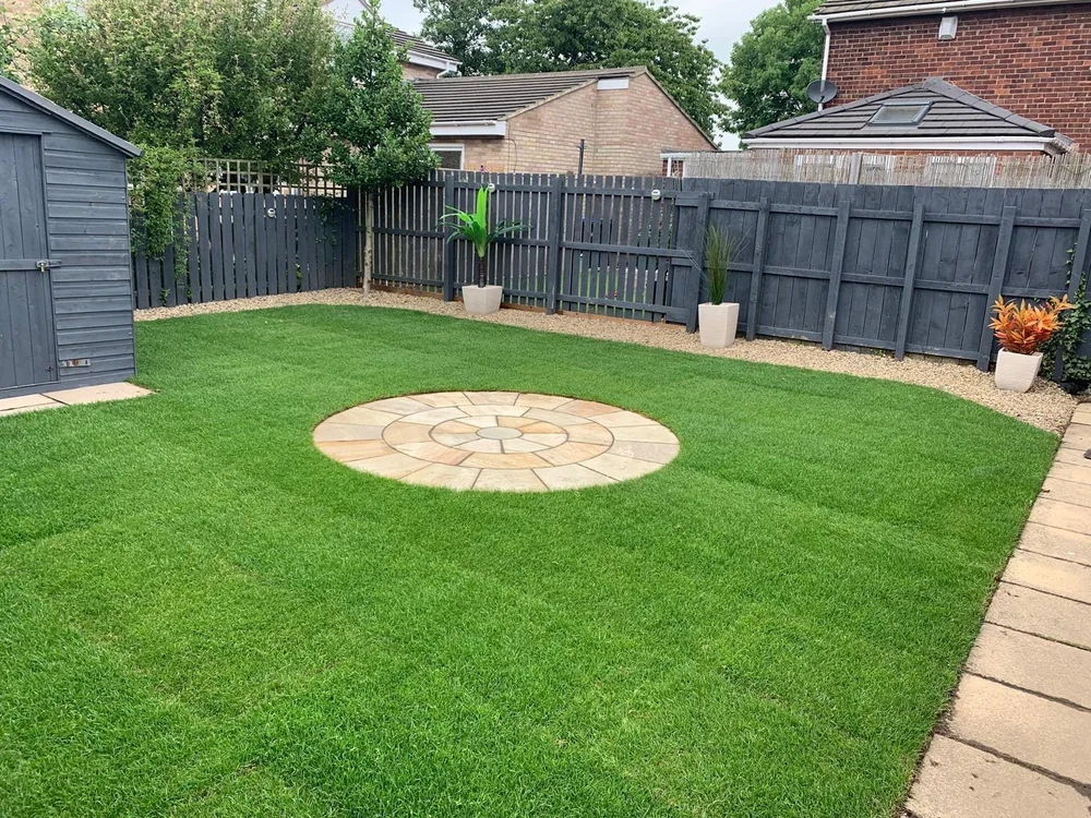 Painted fencing around a new lawn with a sandstone circle