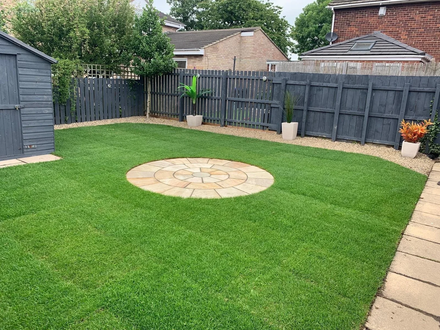 Painted fencing around a new lawn with a sandstone circle